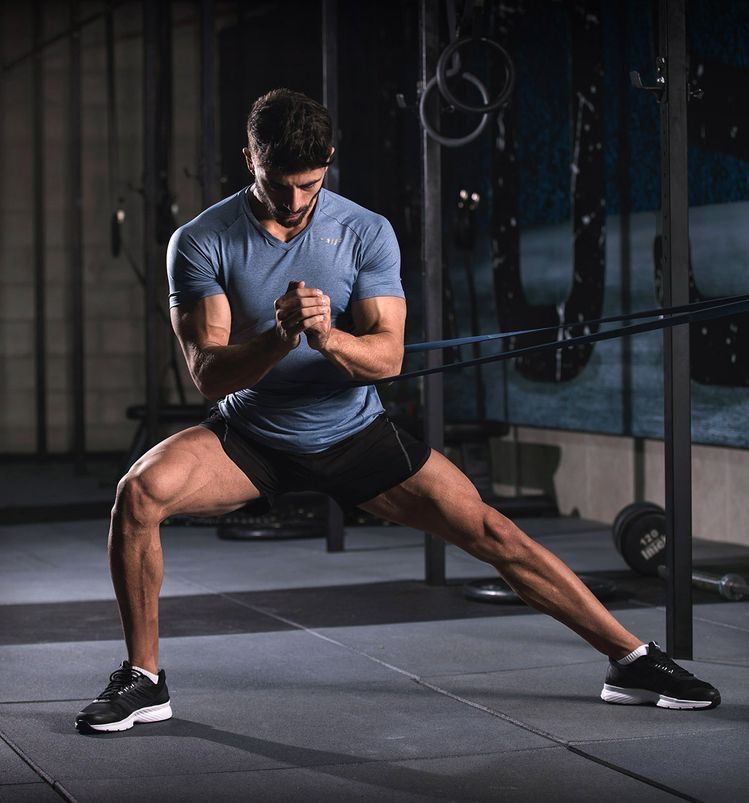 Muscular man pushes a weighted sled on green gym turf.