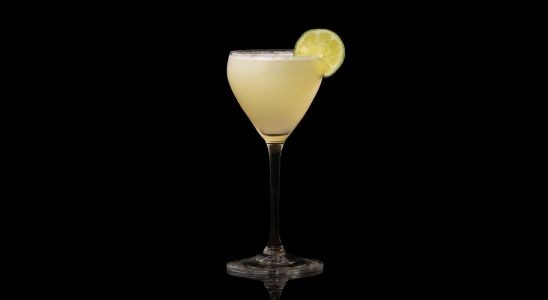 A closeup of a Sour, Summer Key Lime Pie Martini drink against a dark background.