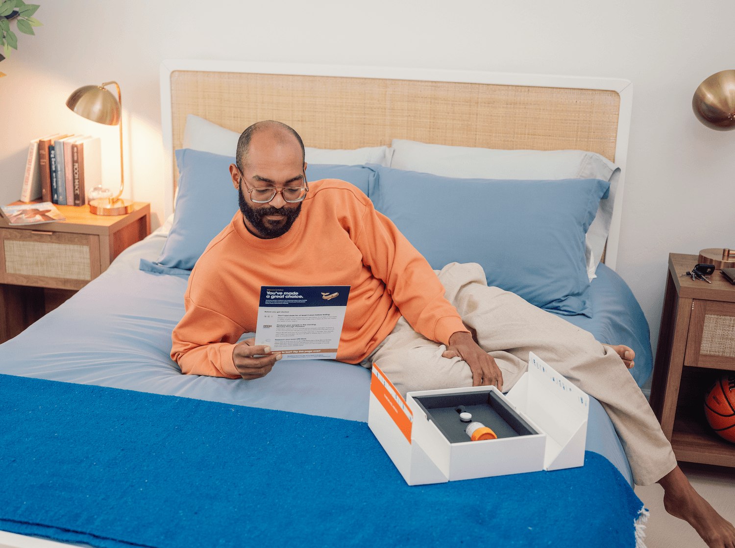 A man looks at the FEllow Semen Analysis kit on his bed
