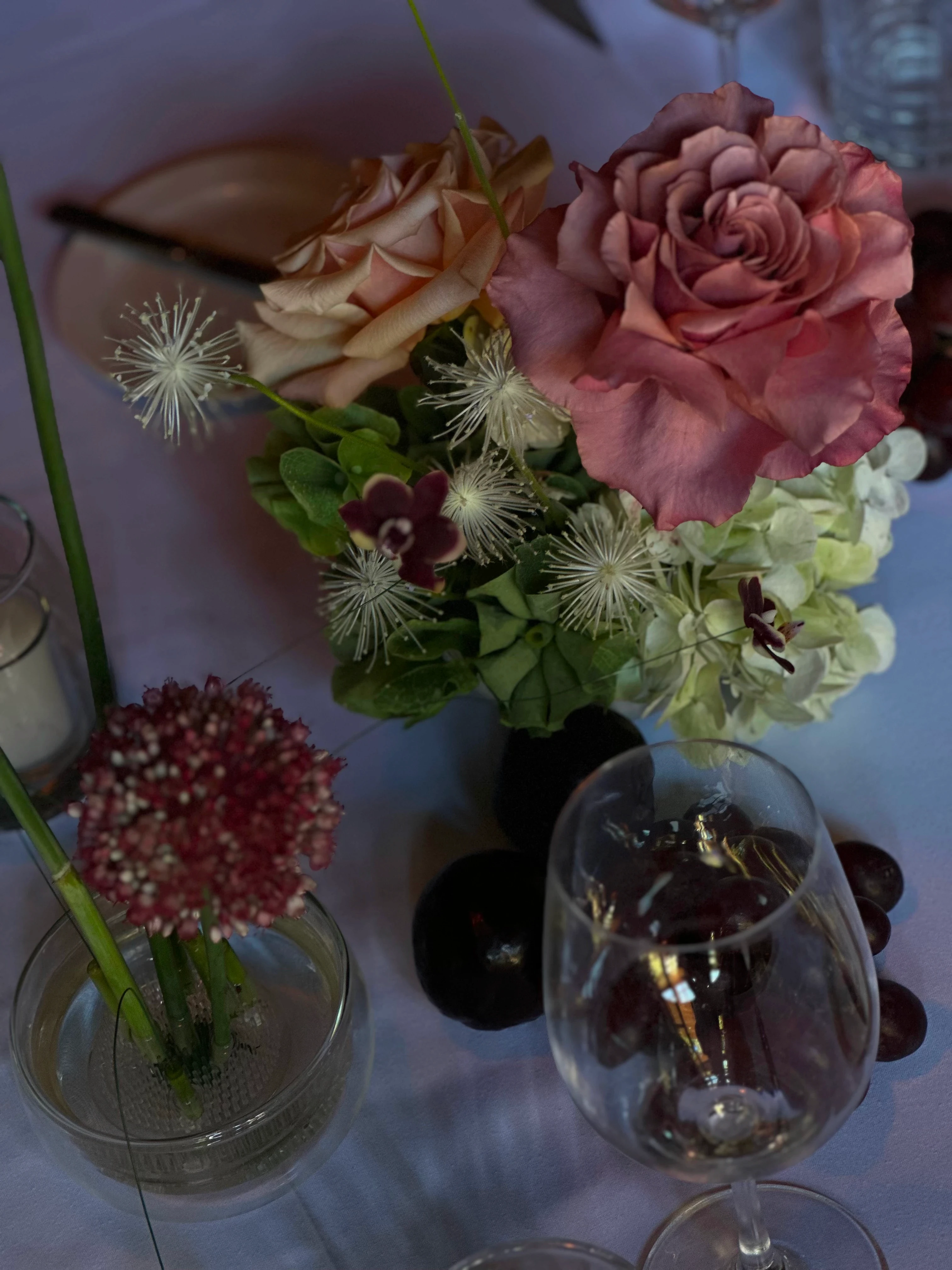 Vista cenital de arreglo floral con rosas rosadas, hortensias y uvas negras en mesa de recepción de Gardiner.