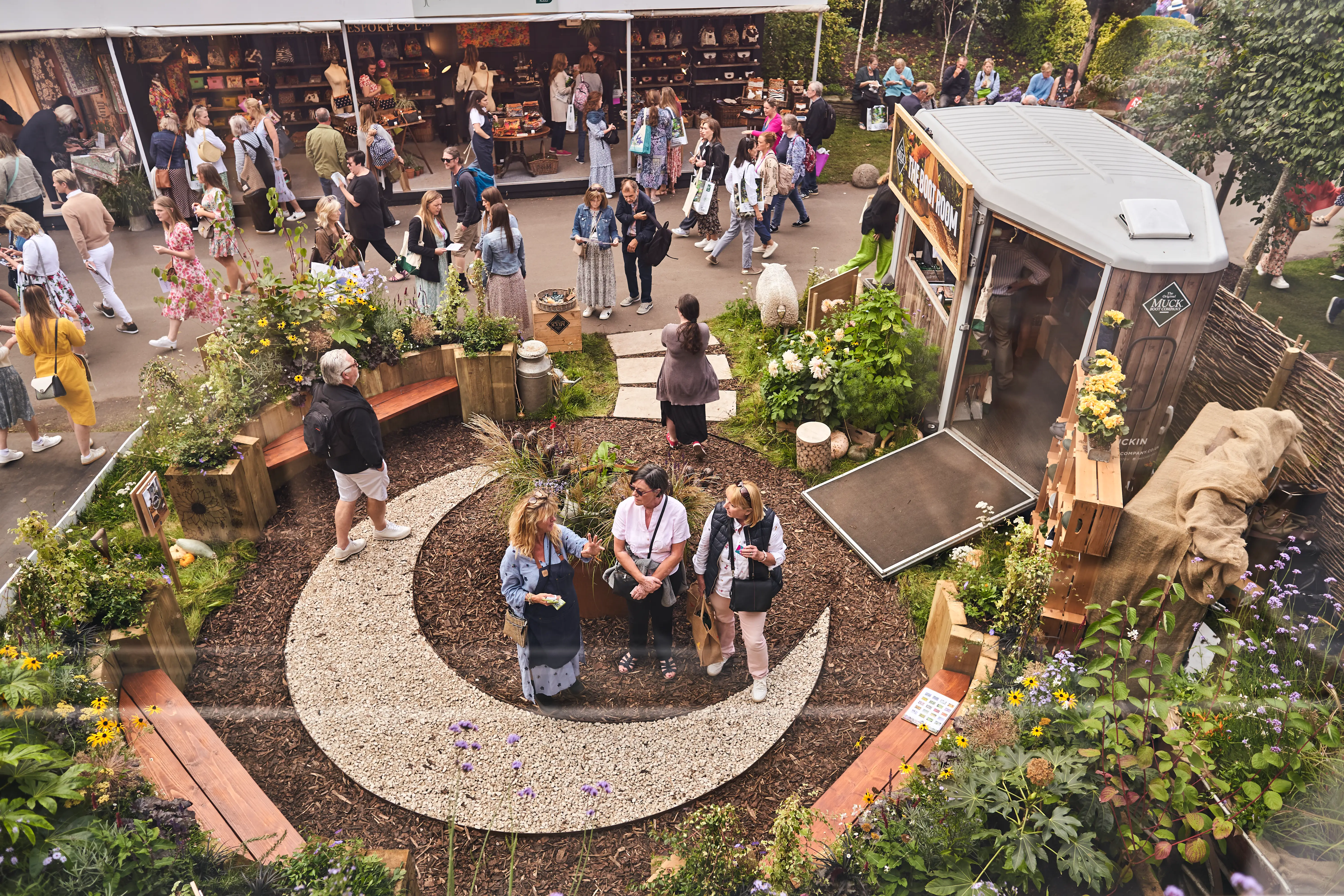 Aerial view of a gathering in a garden with people seated in a circular arrangement surrounded by plants.