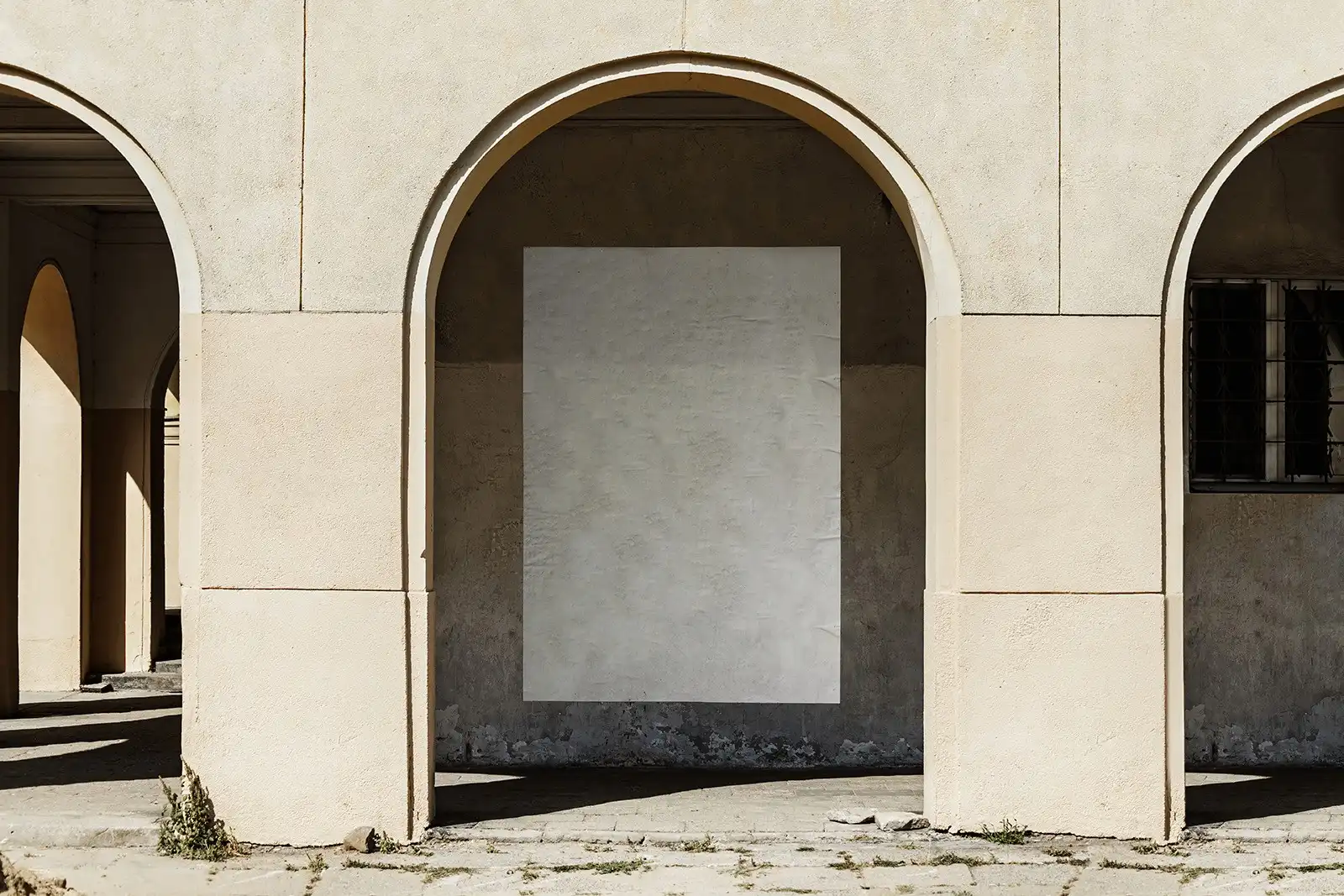 Blue poster mockup with bold white and black typography placed on a worn, textured wall under a sunlit archway. The minimalist design contrasts with the aged stucco surface, creating a dynamic visual.