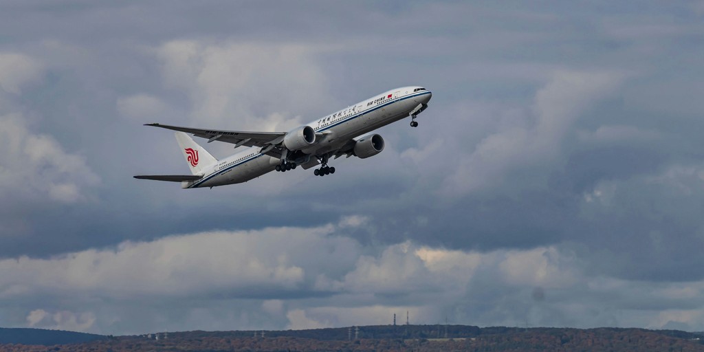 A commercial airplane ascends into a cloudy sky.