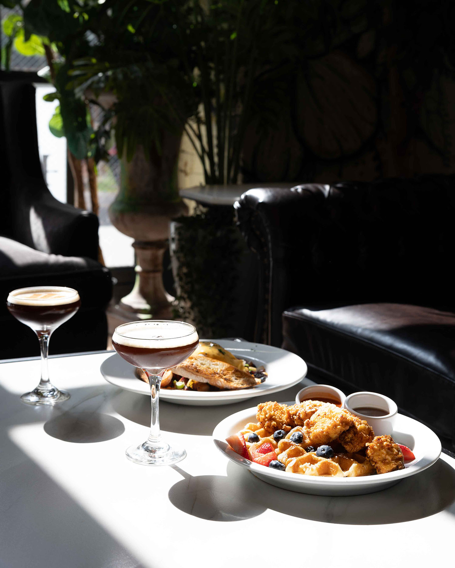 Chicken and waffles with fresh berries and two espresso martinis on a sunlit table at Hubbard Inn in River North Chicago IL