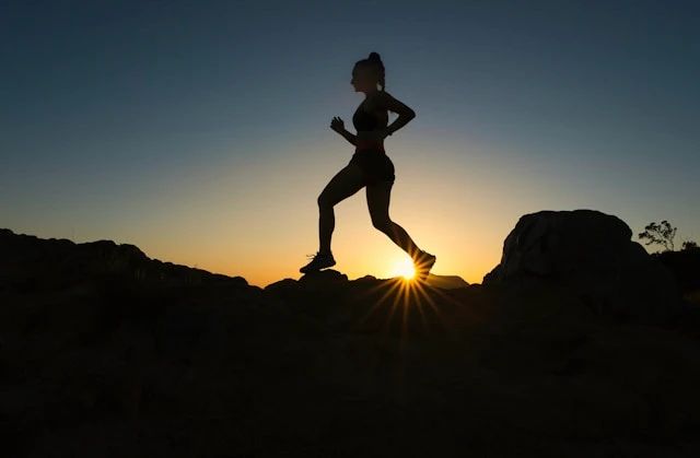 Silhouette of a person jogging outdoors at sunset, building a consistent exercise habit.