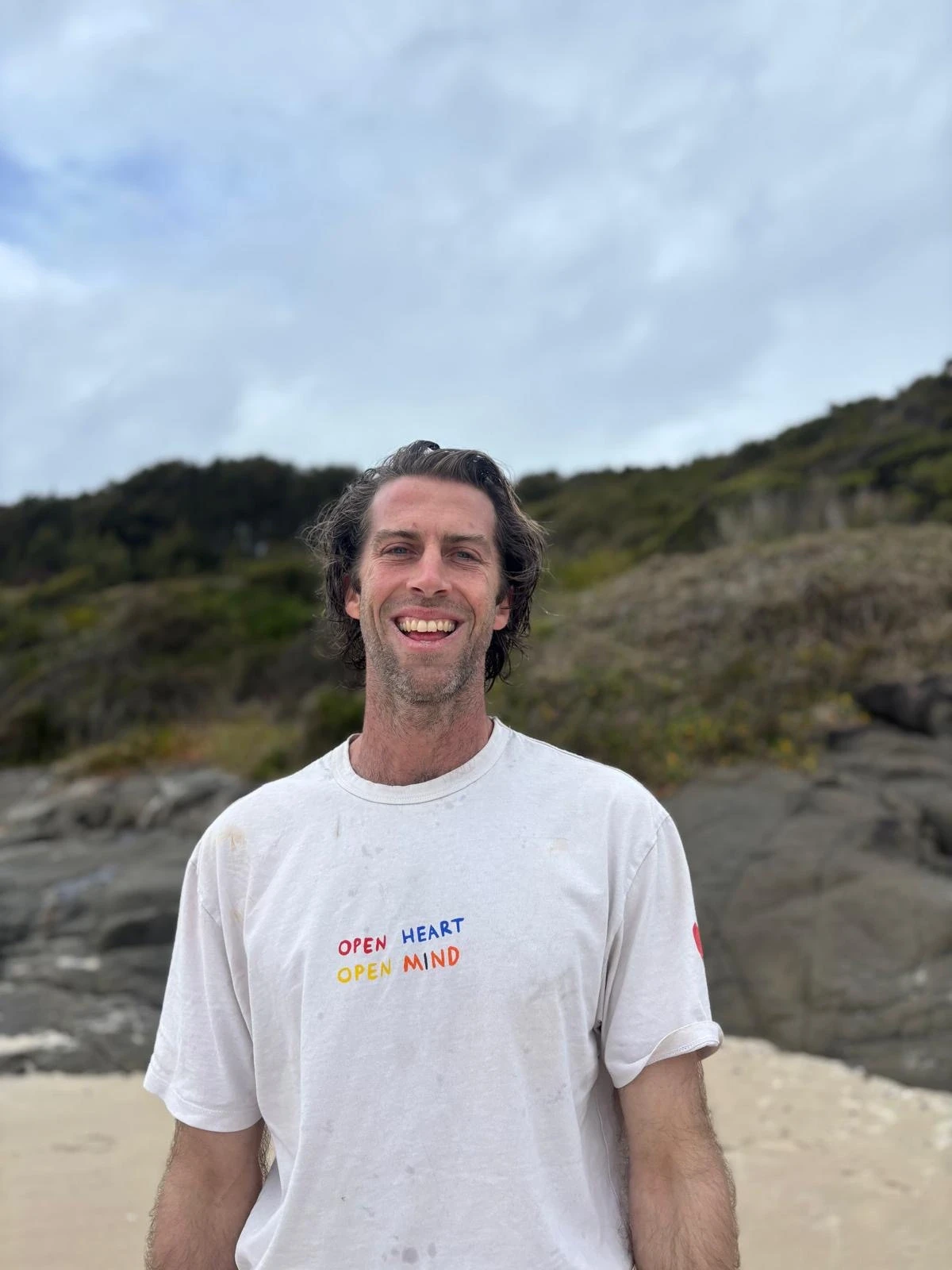 Nic Laidlaw smiling on a beach with a grey sky