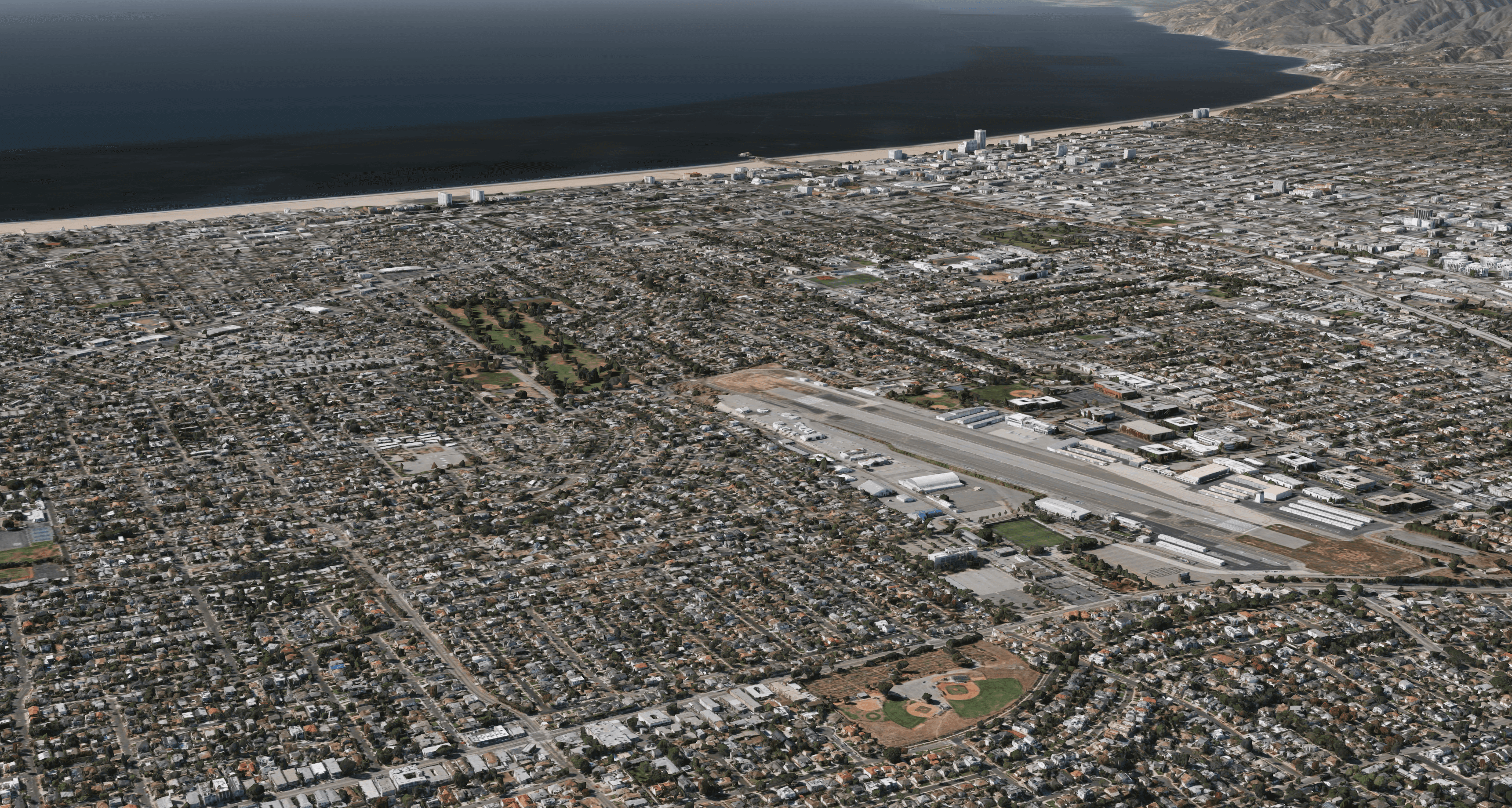 Oblique aerial image of the Santa Monica Airport site within the Santa Monica neighborhood context, with Santa Monica Bay in the distance.