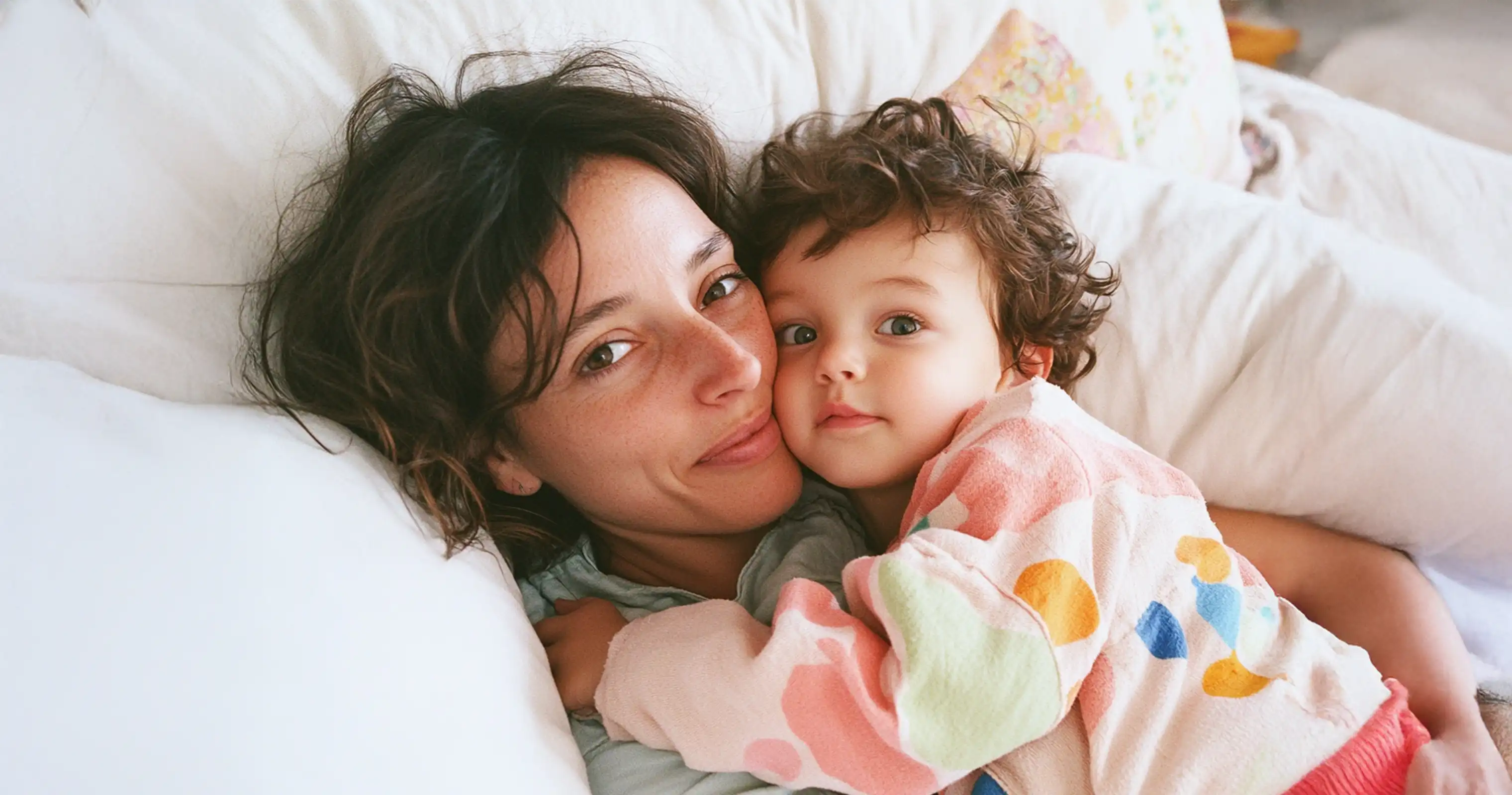 A caring nanny and child cuddling in a cozy bed, illustrating the warmth and security provided by full-time nanny care.