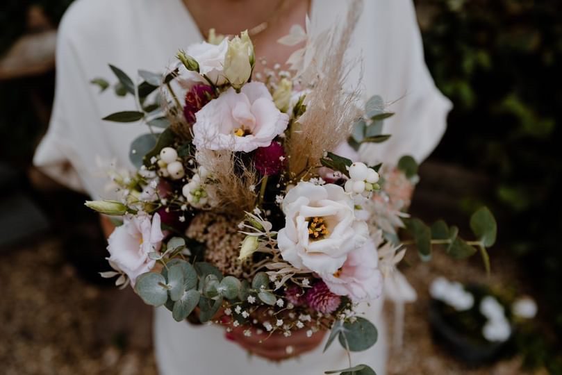 Braut hält einen Strauß mit Rosen, Lisianthus und Eukalyptus