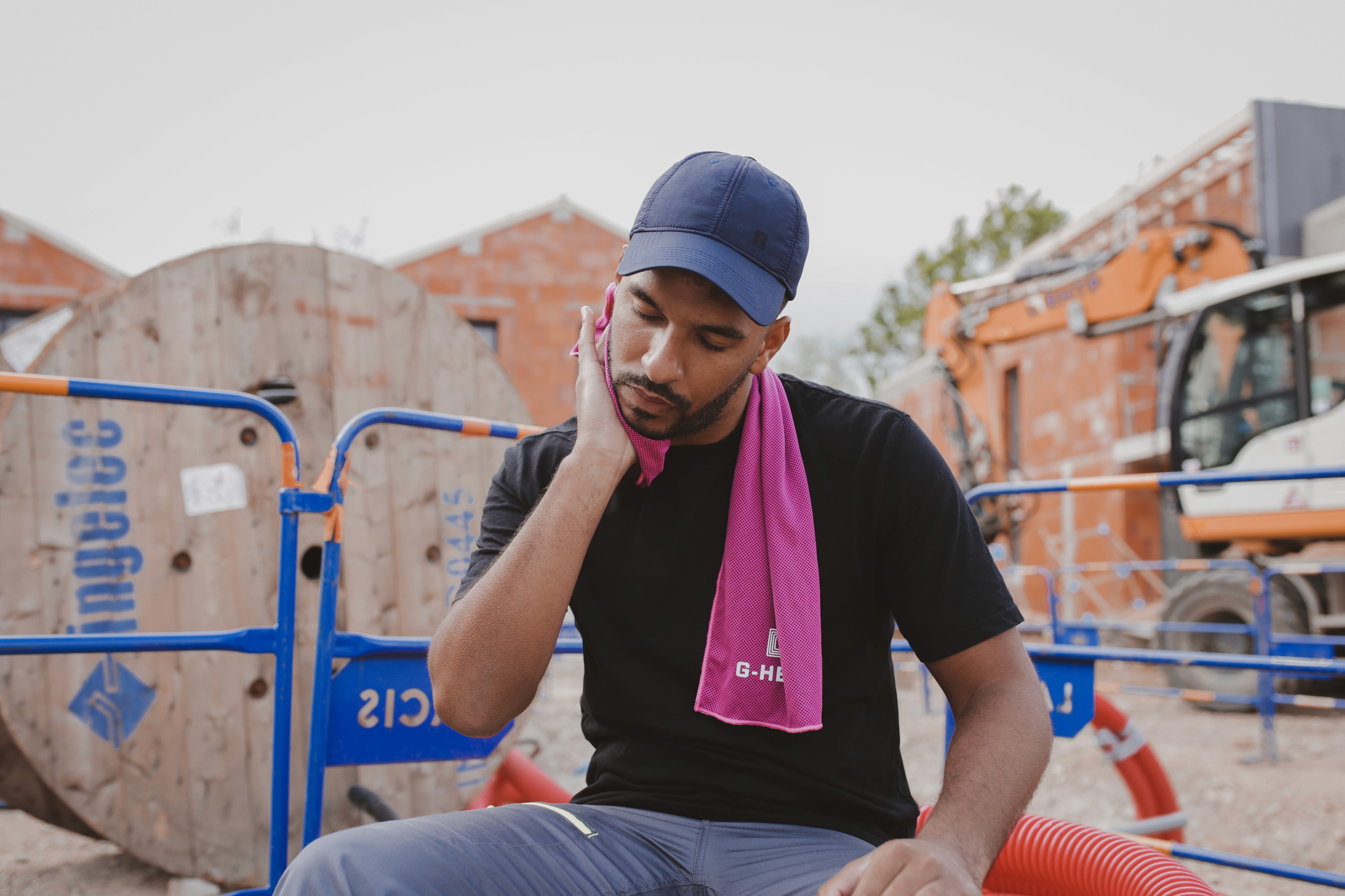 Travailleur sur un chantier de construction utilisant une serviette rafraîchissante G-Heat pour se refroidir pendant une pause en environnement chaud.