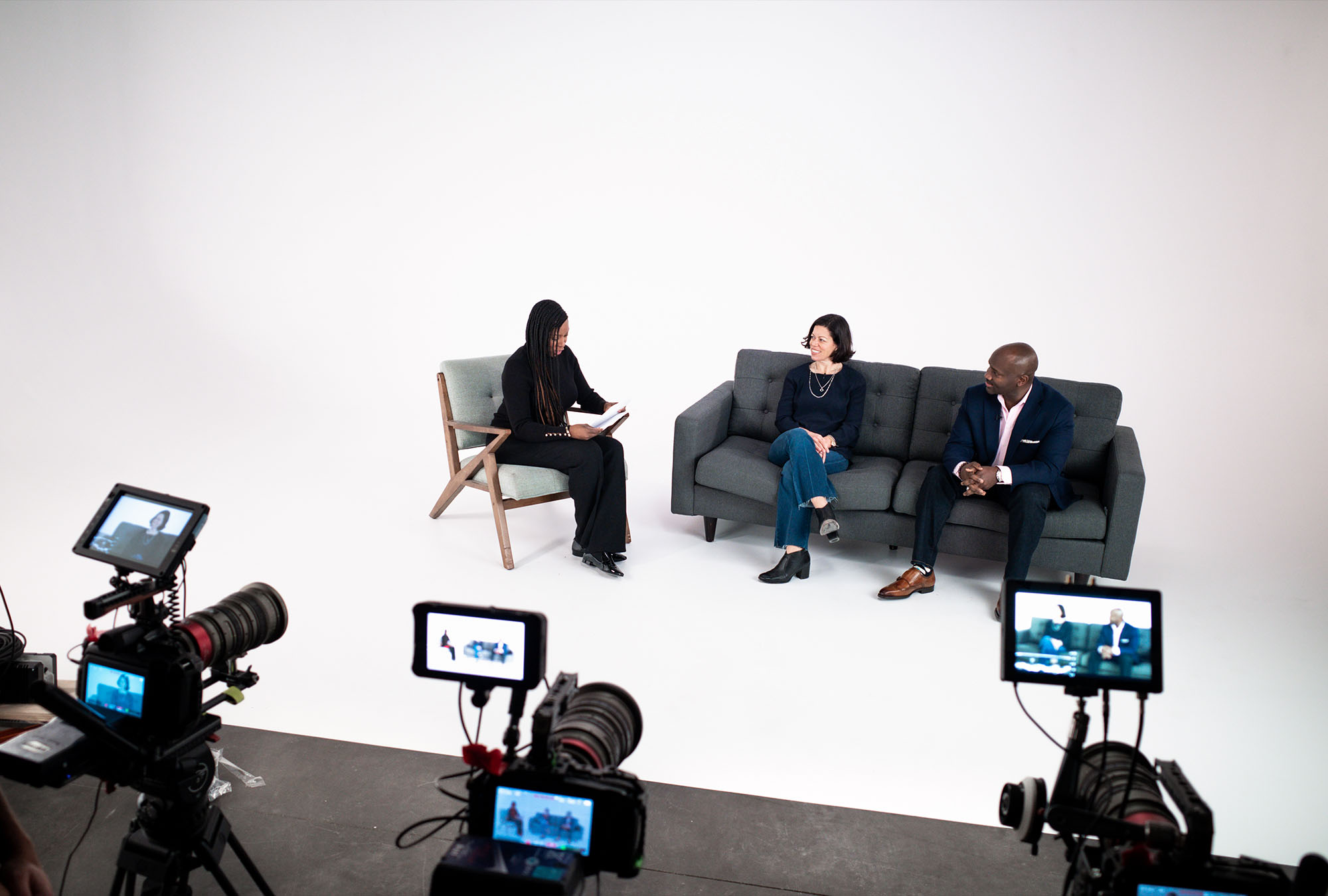Three members of Amazons DEI team sit on the soundstage at Particle Studio in Seattle WA. They are interviewing each other in front of three large cameras with a white background.