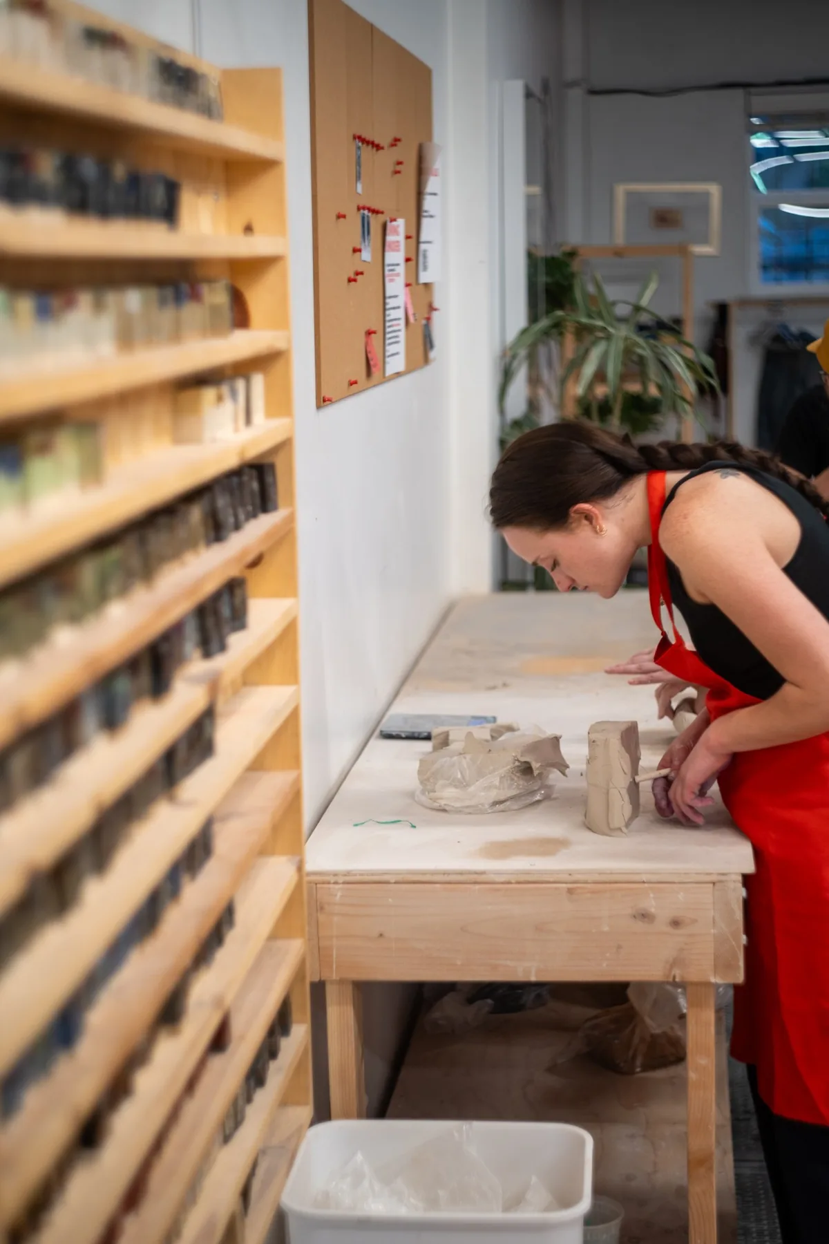 Member hand-building with a slab of clay at the long worktable at Kinship Studio in Denver