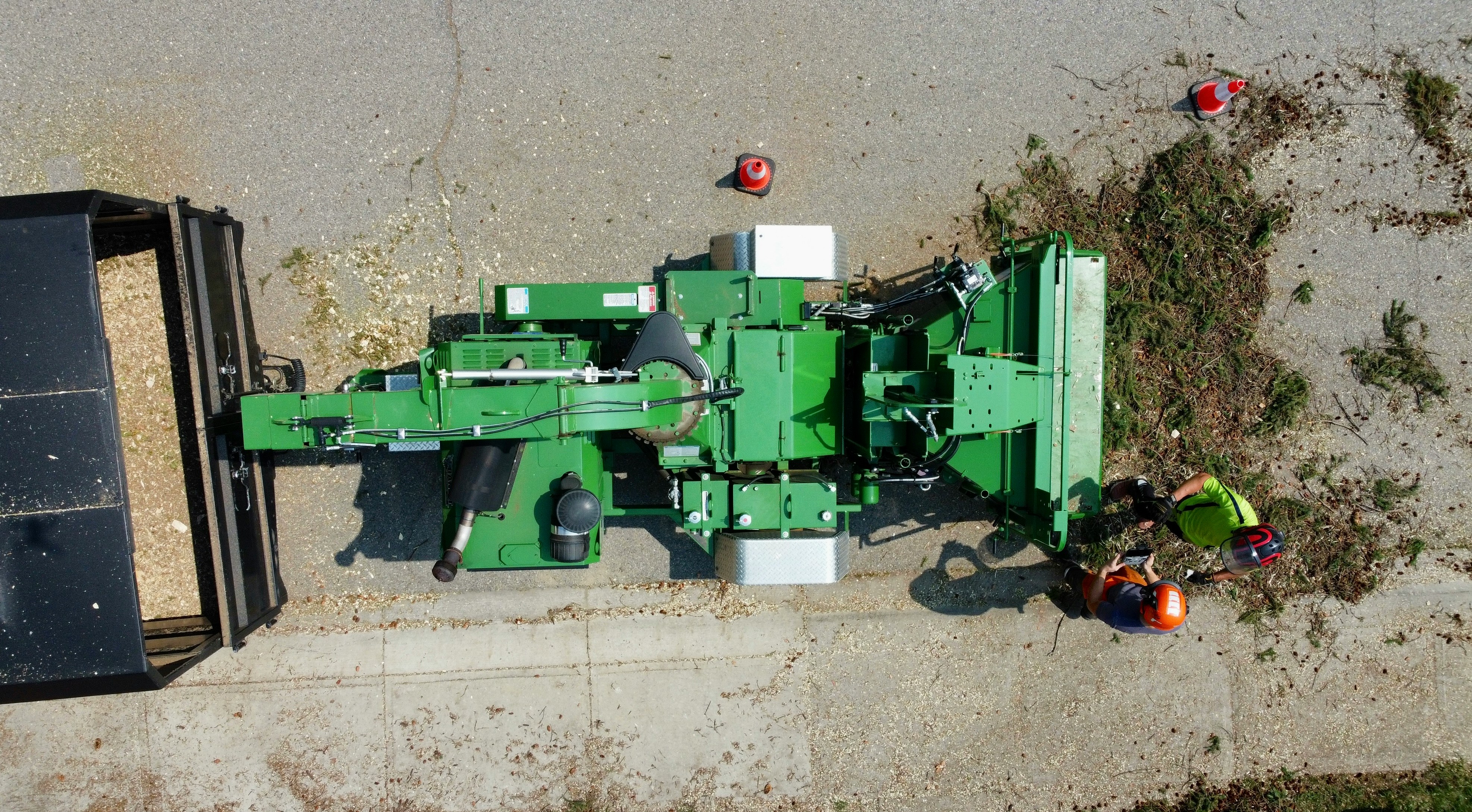 Green agricultural machine processing materials near a trailer.