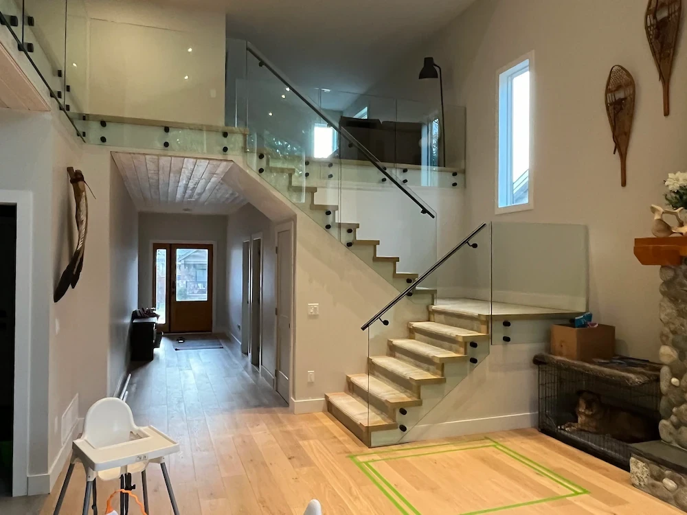 Minimalist interior balcony and staircase with semi-frameless glass railings and modern recessed lighting.