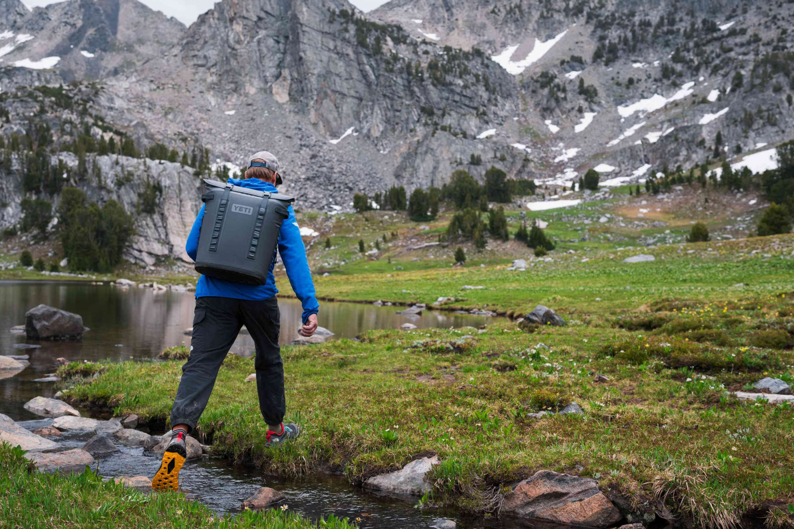 Man hiking along a trail sporting a YETI backpack.