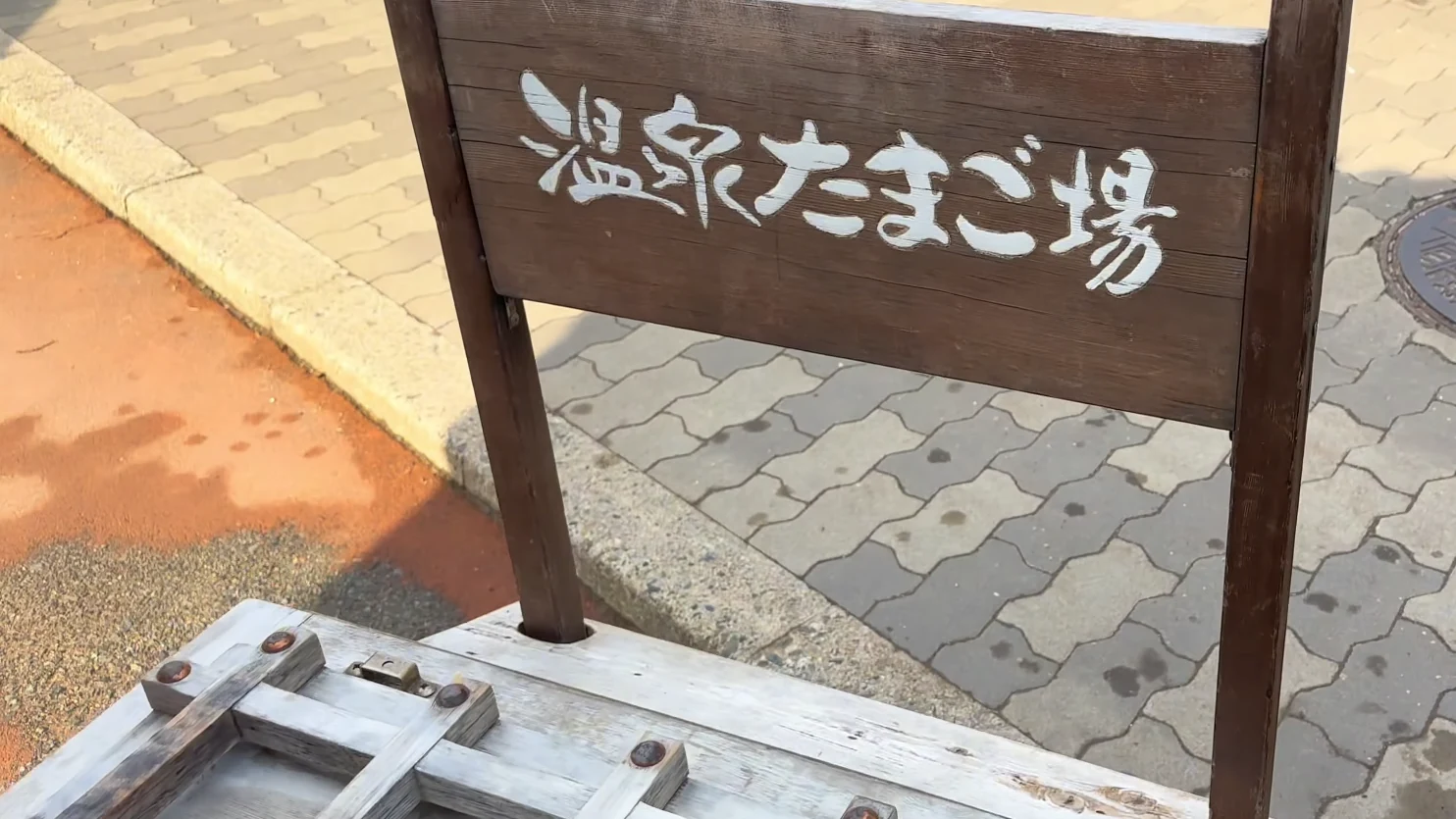 A weathered timber sign reading Onsen Tamago Station beside the Kinosaki hot spring vent.