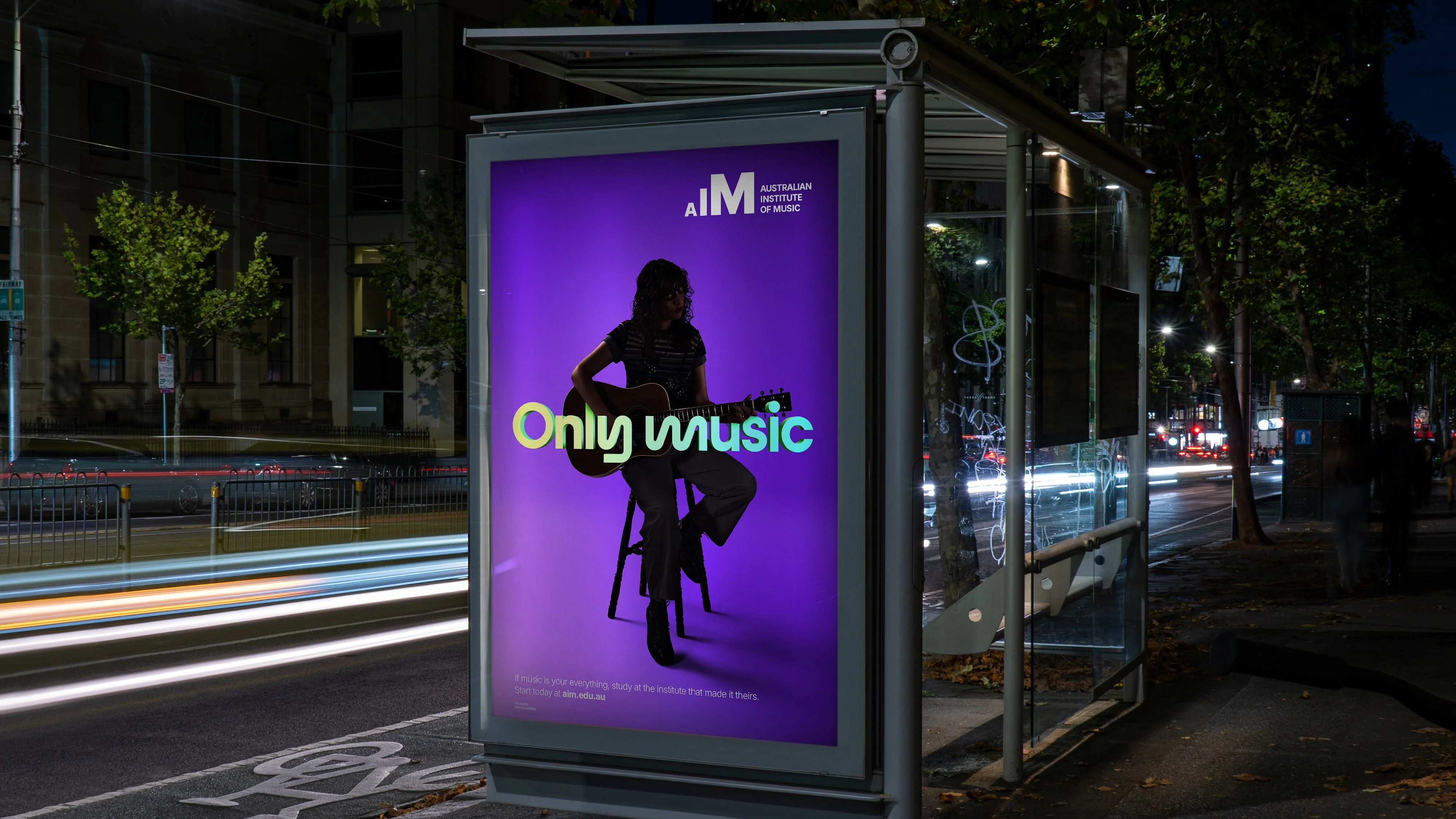 Only Music poster for the Australian Institute of Music at a night-time bus shelter, showing a seated guitarist