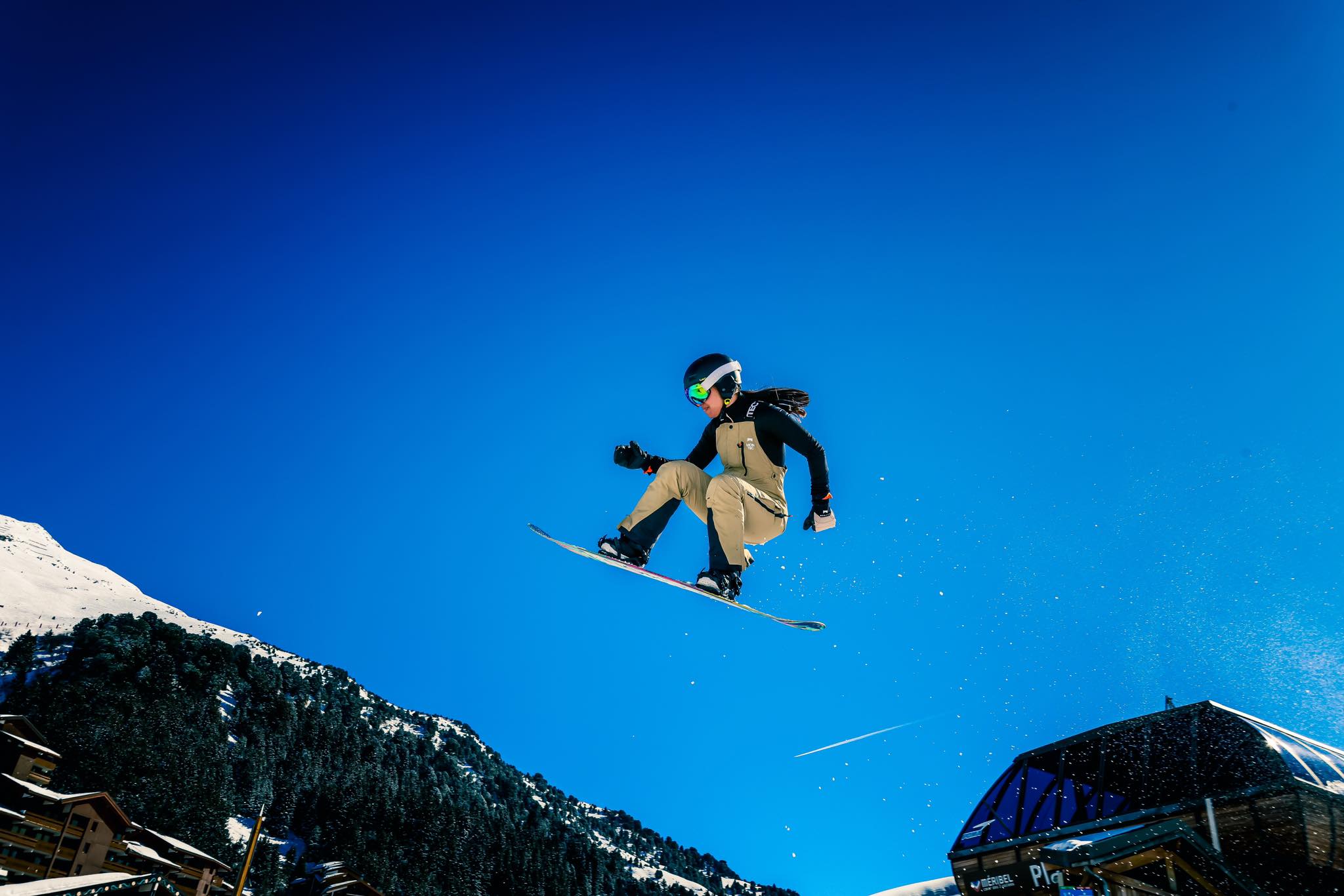 A woman kicking a snowboard in the air.