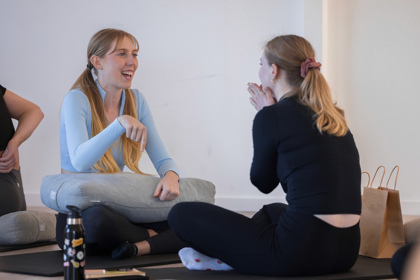 Two women sitting cross legged on the floor laughing