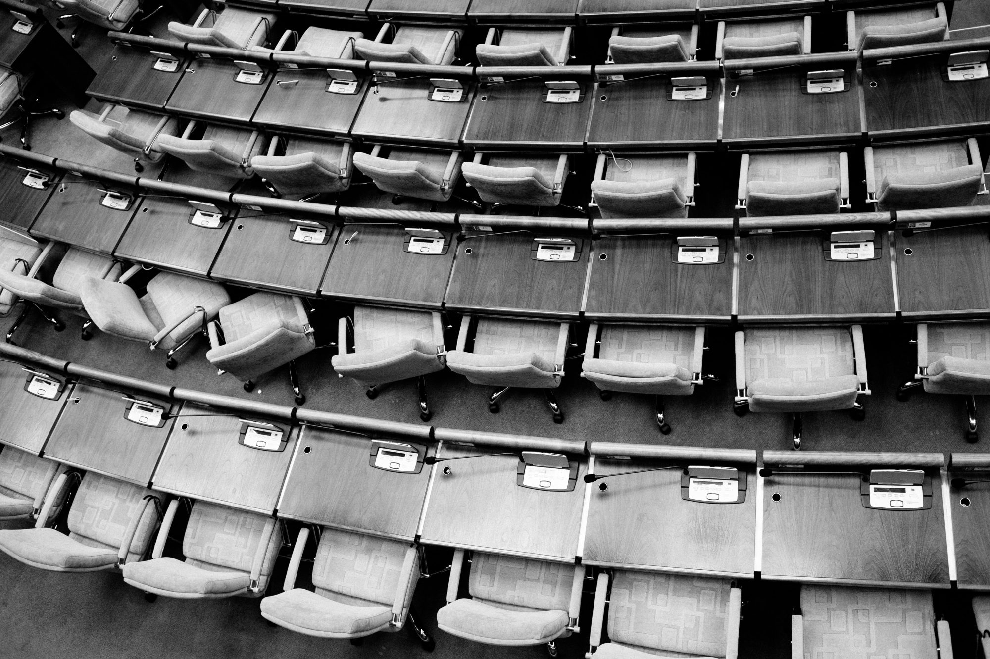 Aerial view of empty, curved rows of seats in a modern auditorium, captured in black and white.