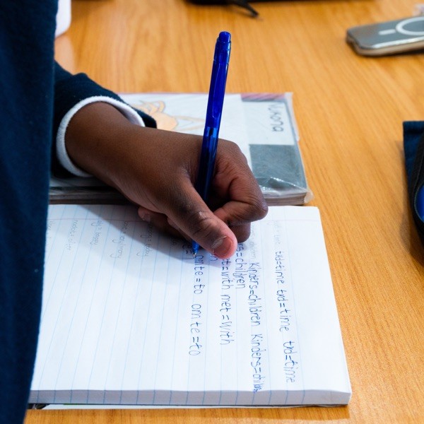 A learner writing in a notebook