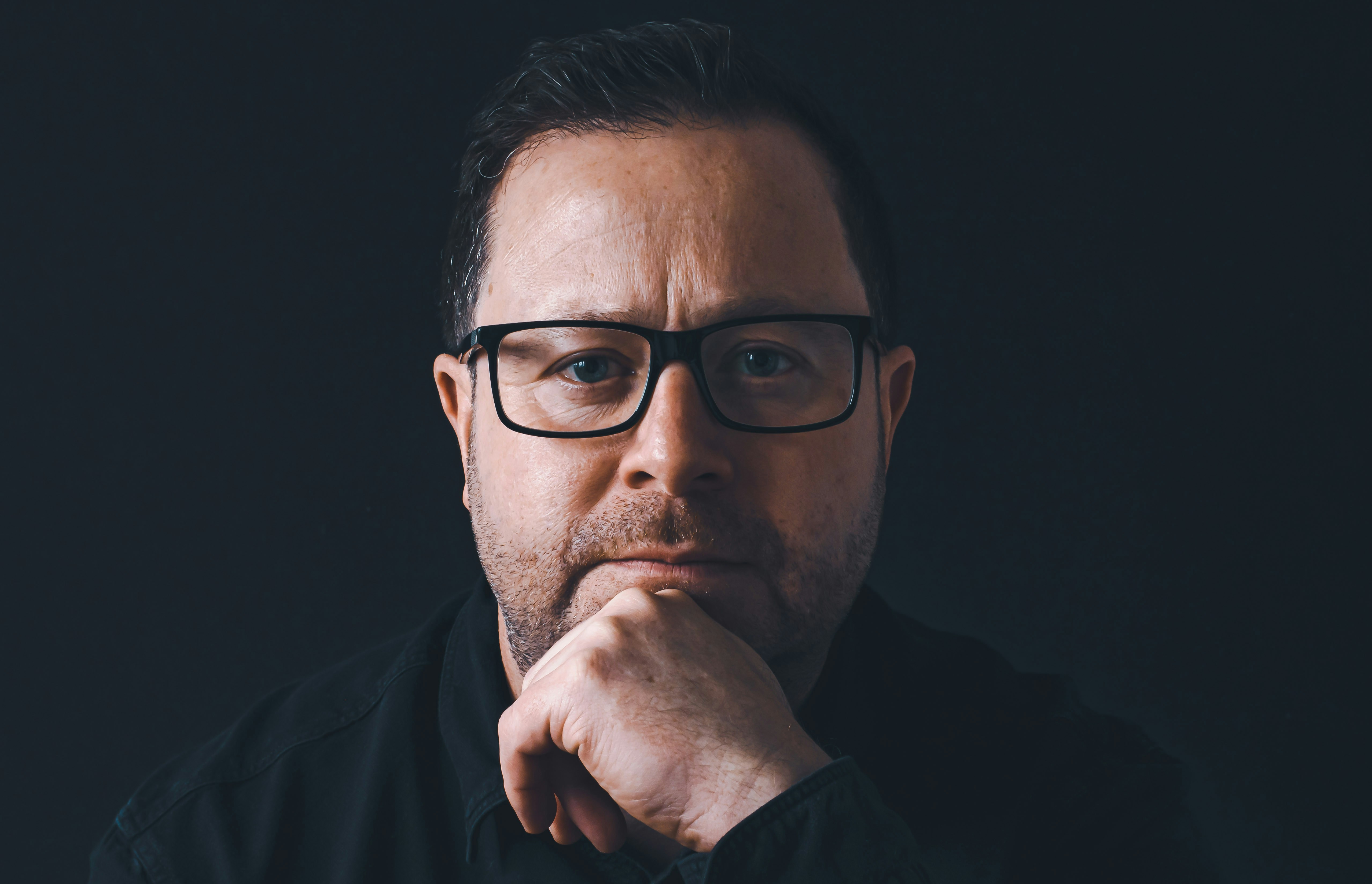 a man with glasses is posing for a picture