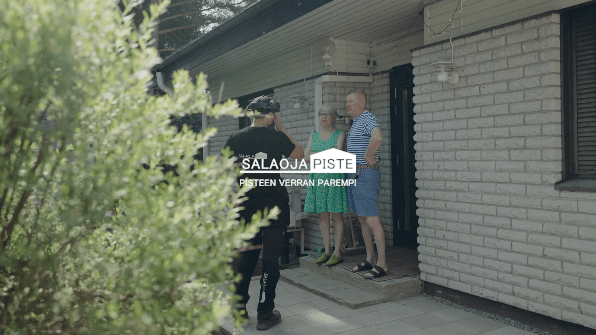 Insinööri selittää salaojasuunnitelmaa asiakkaalle työmaalla, pitäen piirustuksia kädessä