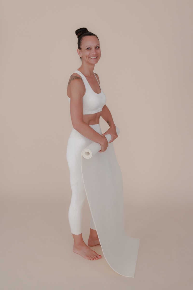 Frau rollt Yoga-Matte ein