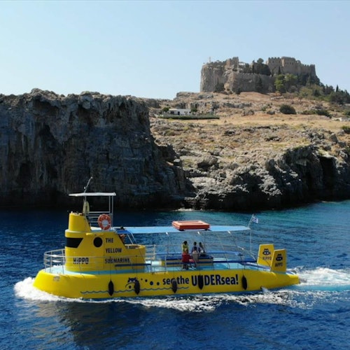 A yellow submarine-like boat on blue water with cliffs and an ancient castle in the background.