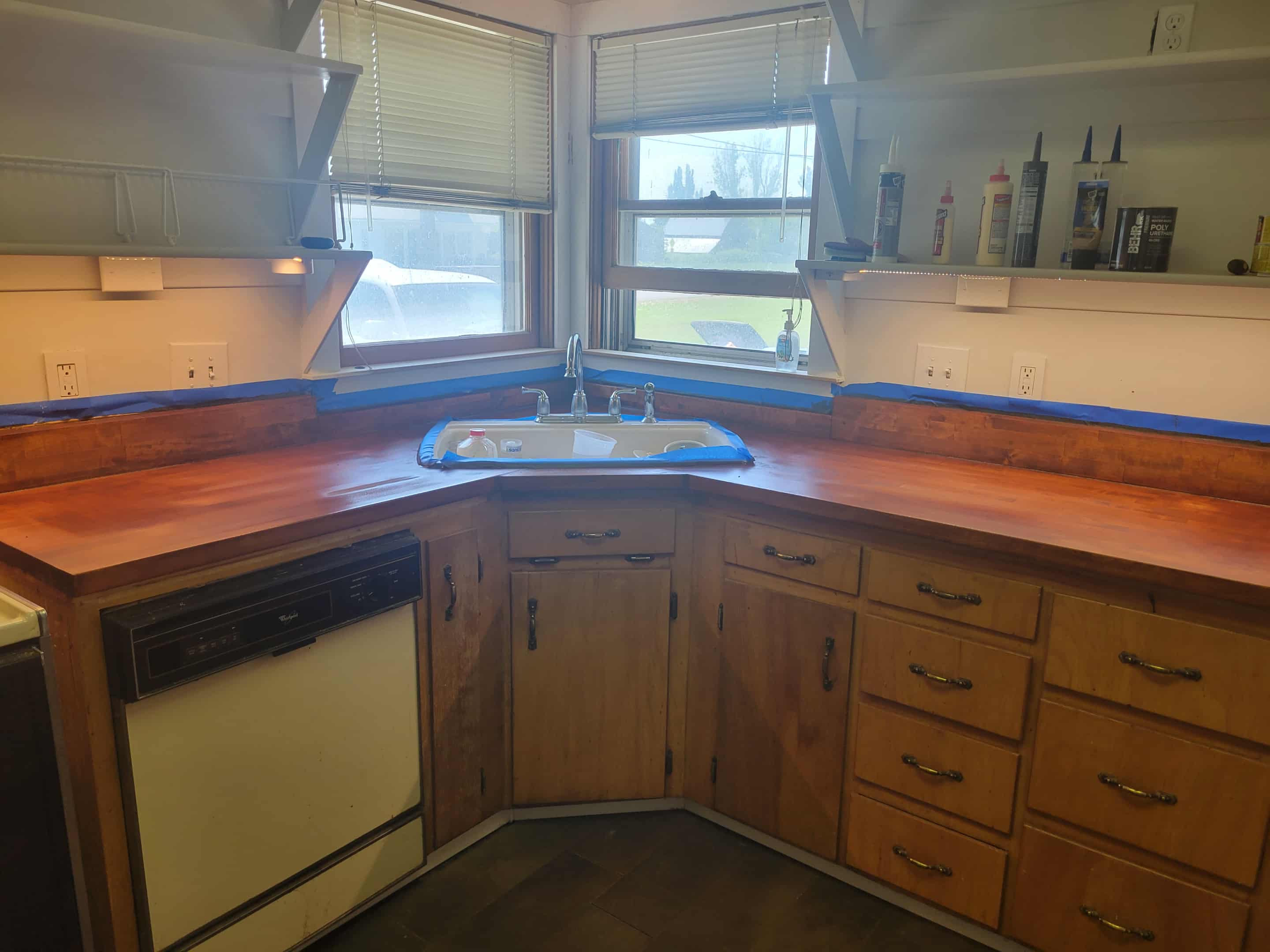 A cozy kitchen featuring wooden cabinets, a curved countertop, and natural light from nearby windows.
