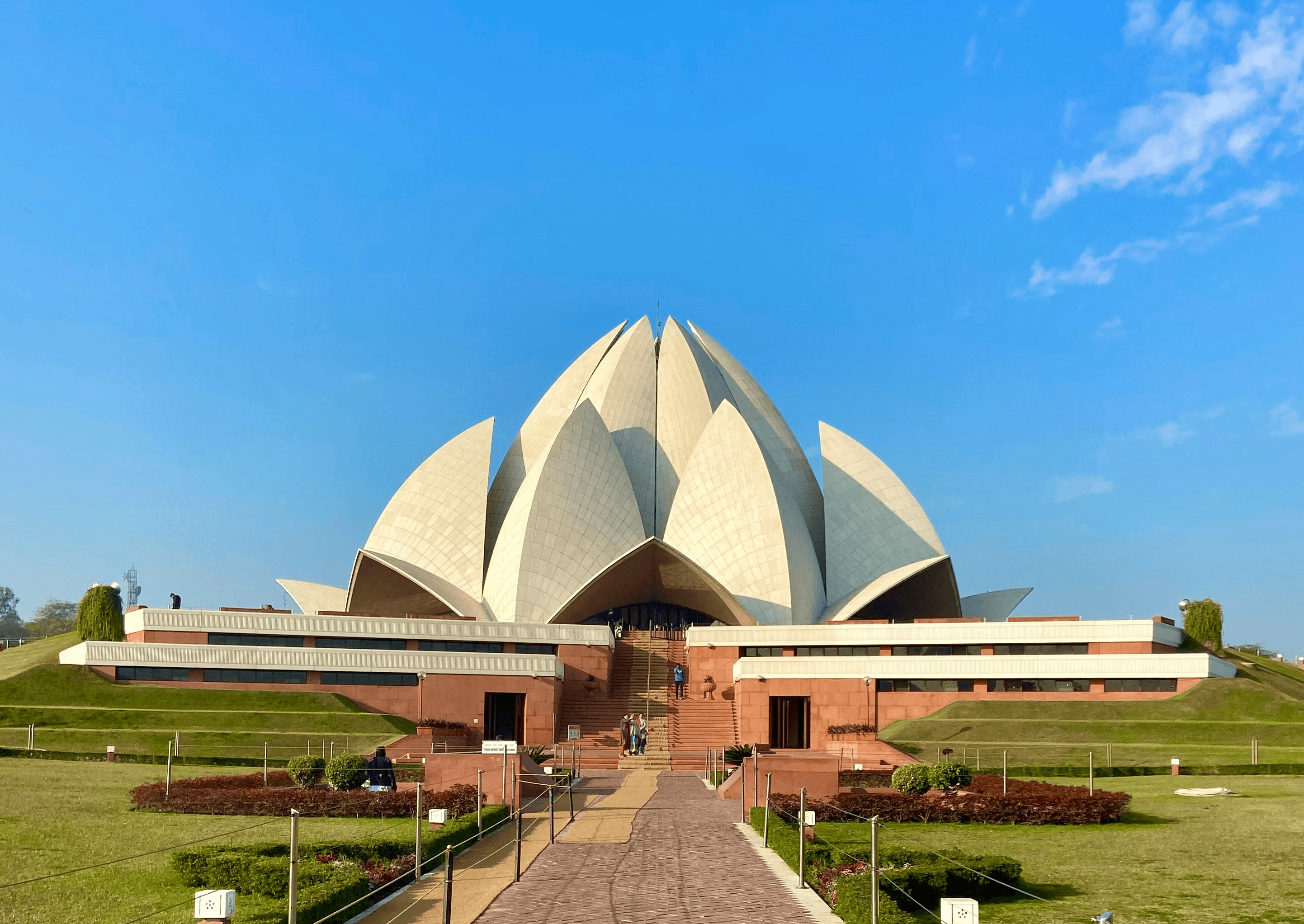 Image of the Lotus Temple in Delhi under a clear blue sky.