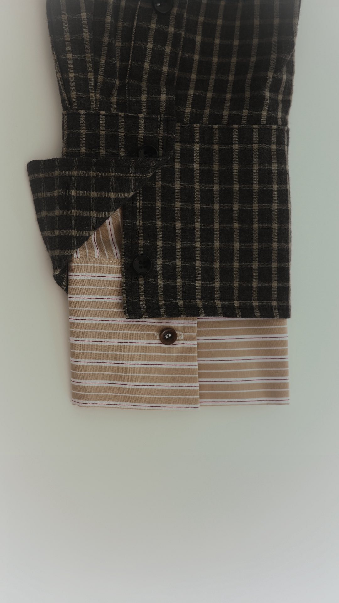 Détail de 2 poignées de chemise l'une dans l'autre à carreaux noirs et rayures rouges dans le lookbook Rita Row