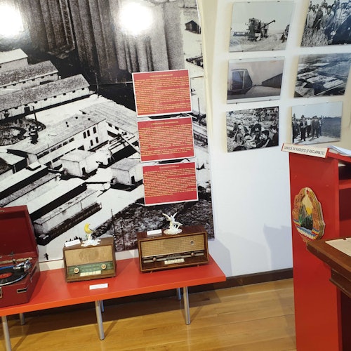 Exhibit includes vintage radios, a record player, historical black-and-white photos, and descriptive text panels on a wall.