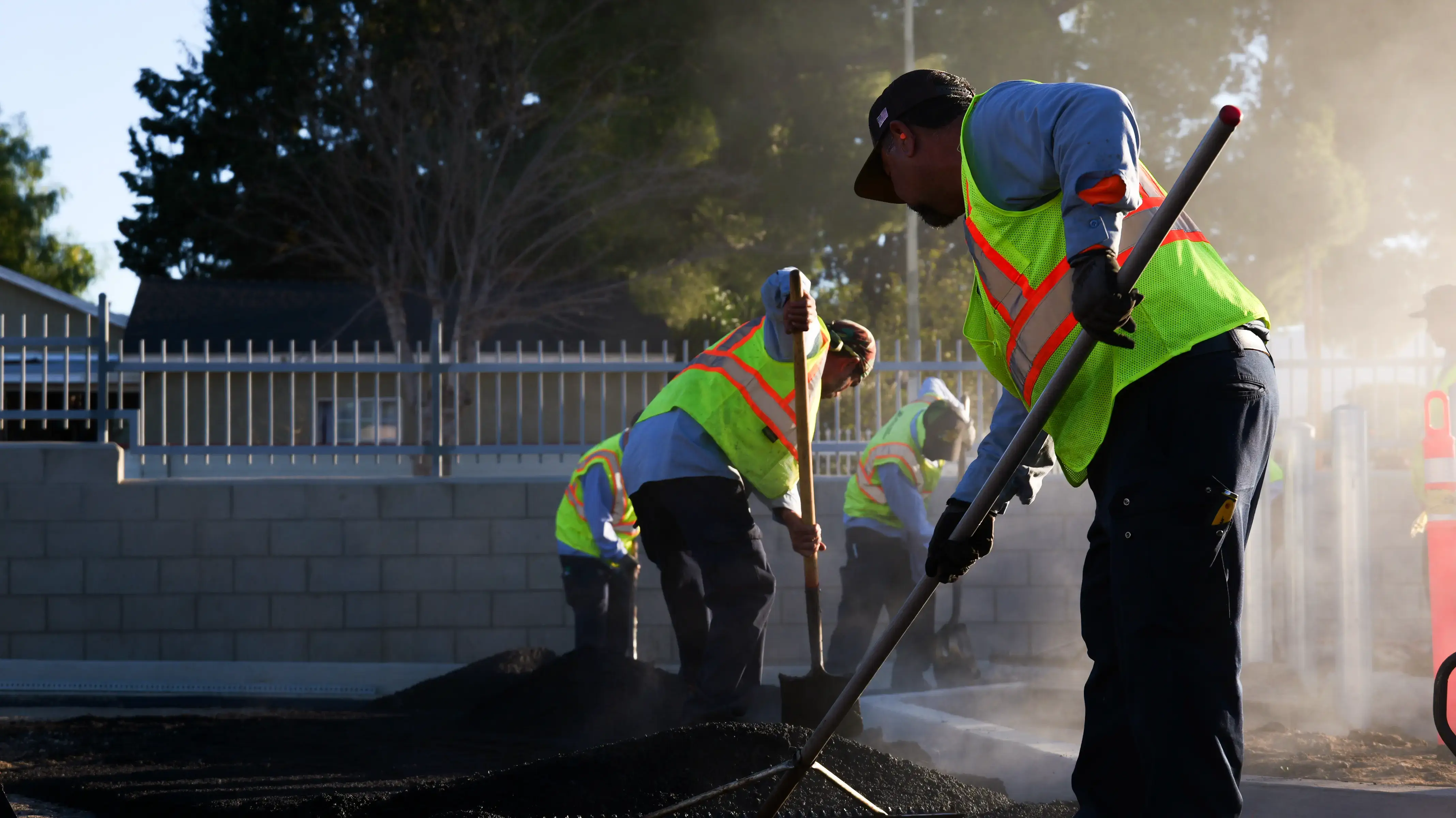 Asphalt crew member raking new pavement