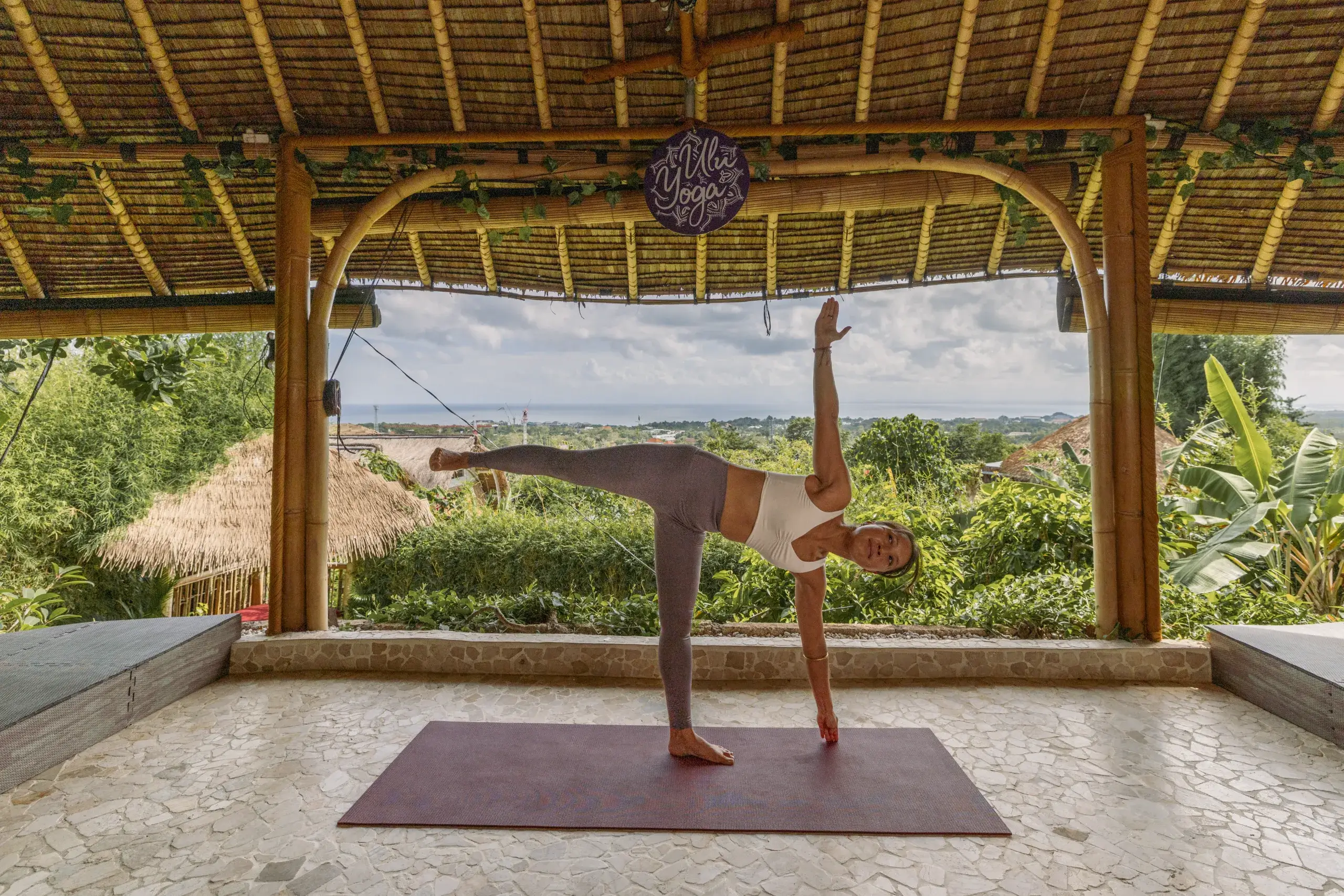 Advanced alignment practice in Half Moon pose Ardha Chandrasana inside the ocean-view bamboo shala for the 300-hour yoga certification in Bali