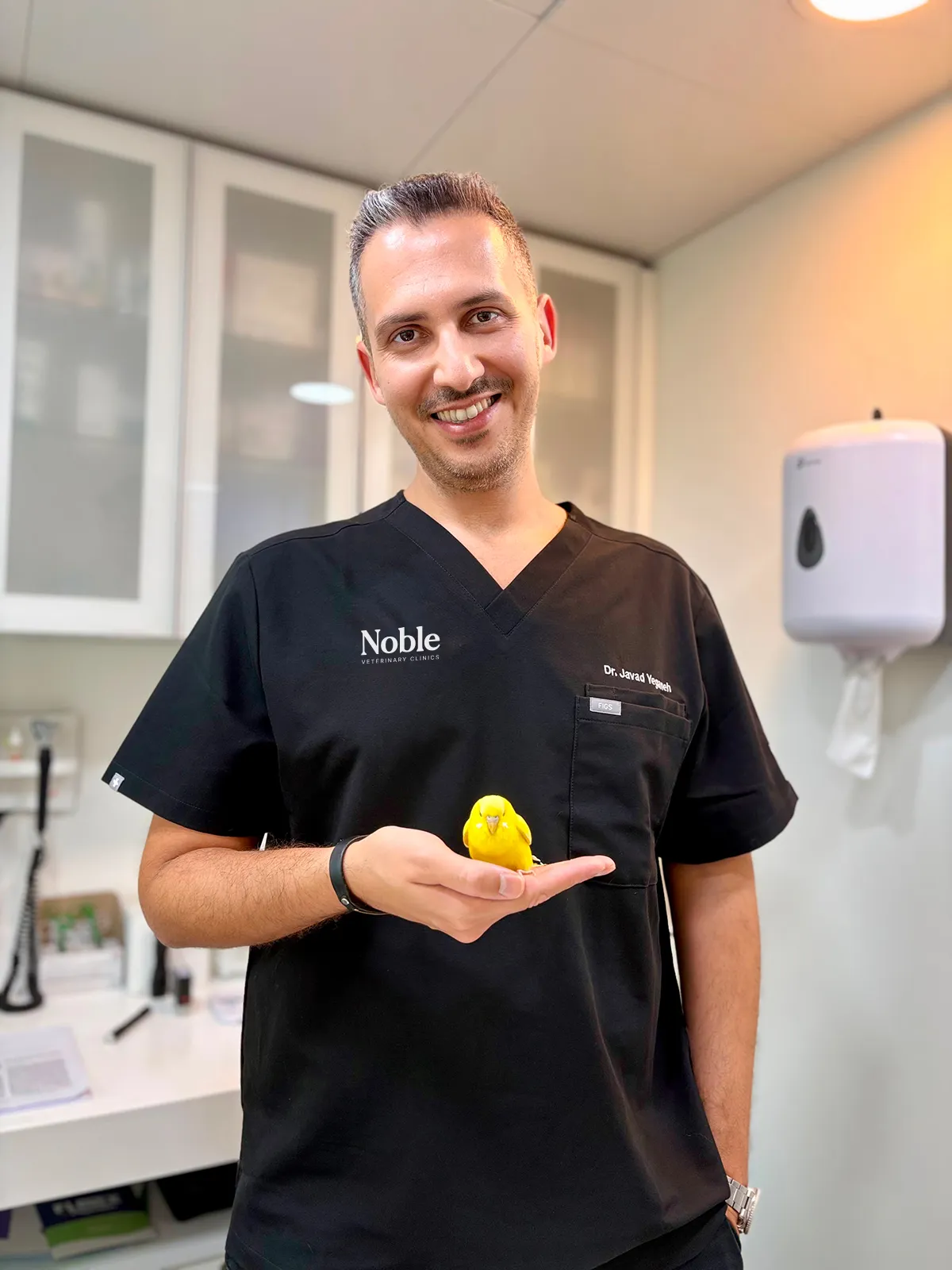 Dr. J. Yeganeh, avian veterinarian at Noble Veterinary Clinics Dubai, gently holding a pet bird during a wellness checkup