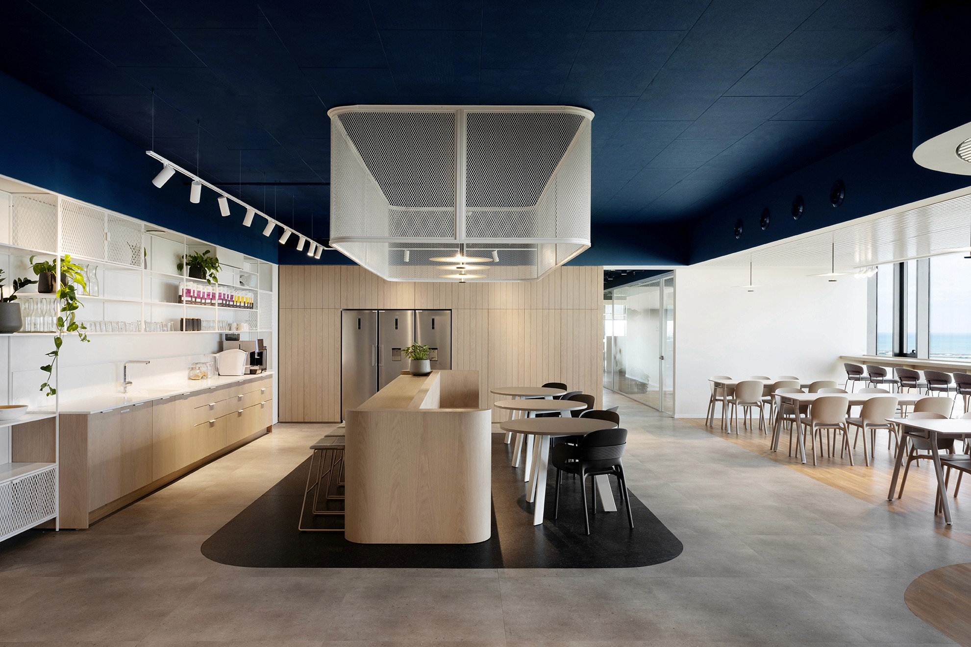 Modern office kitchen area at Bluegen offices in Haifa with light wood finishes and dark ceiling