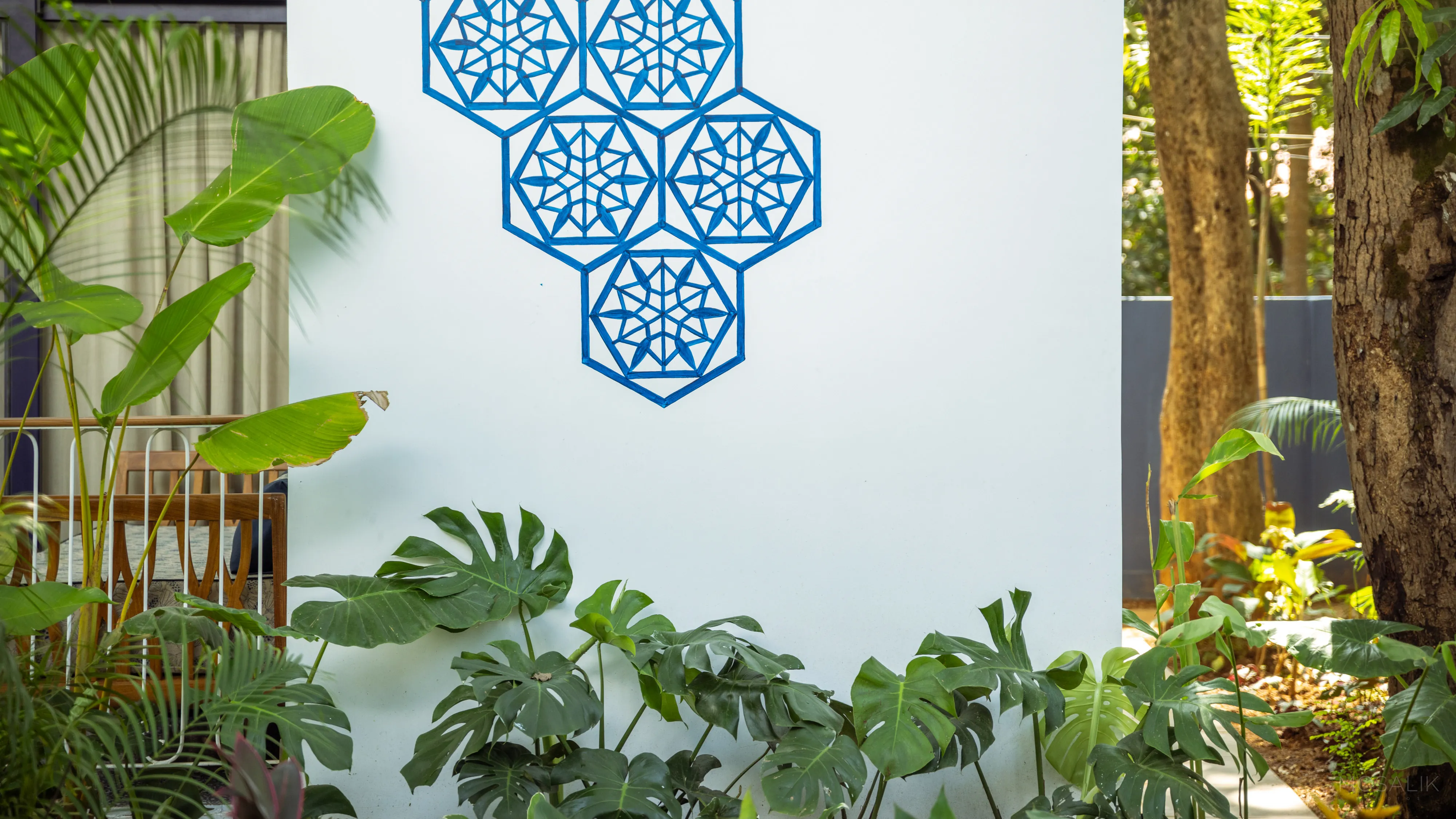 Hand-painted blue jaali motif above a planted courtyard at Jaali Blue
