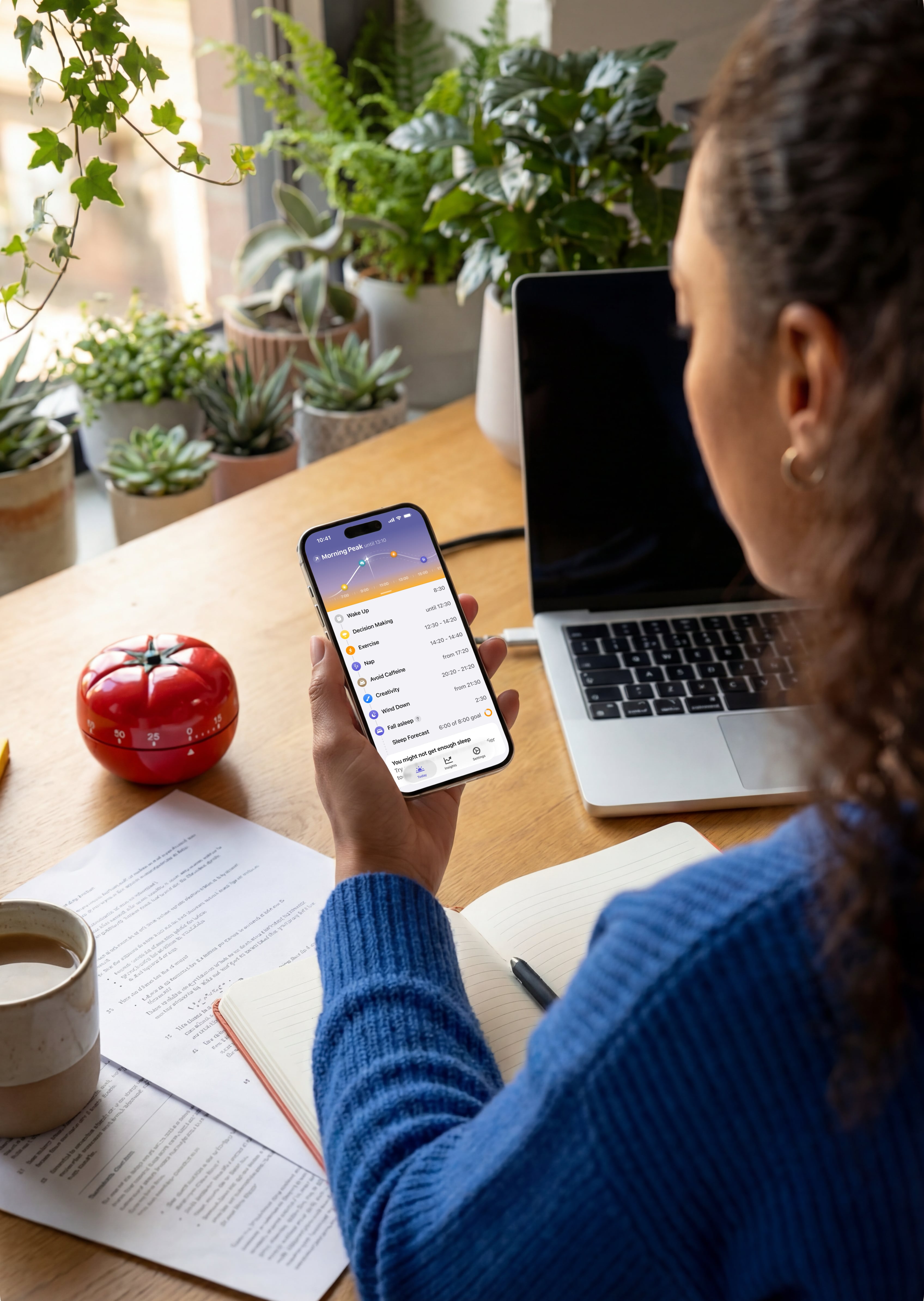 A woman at a desk checking her phone, peaks opened