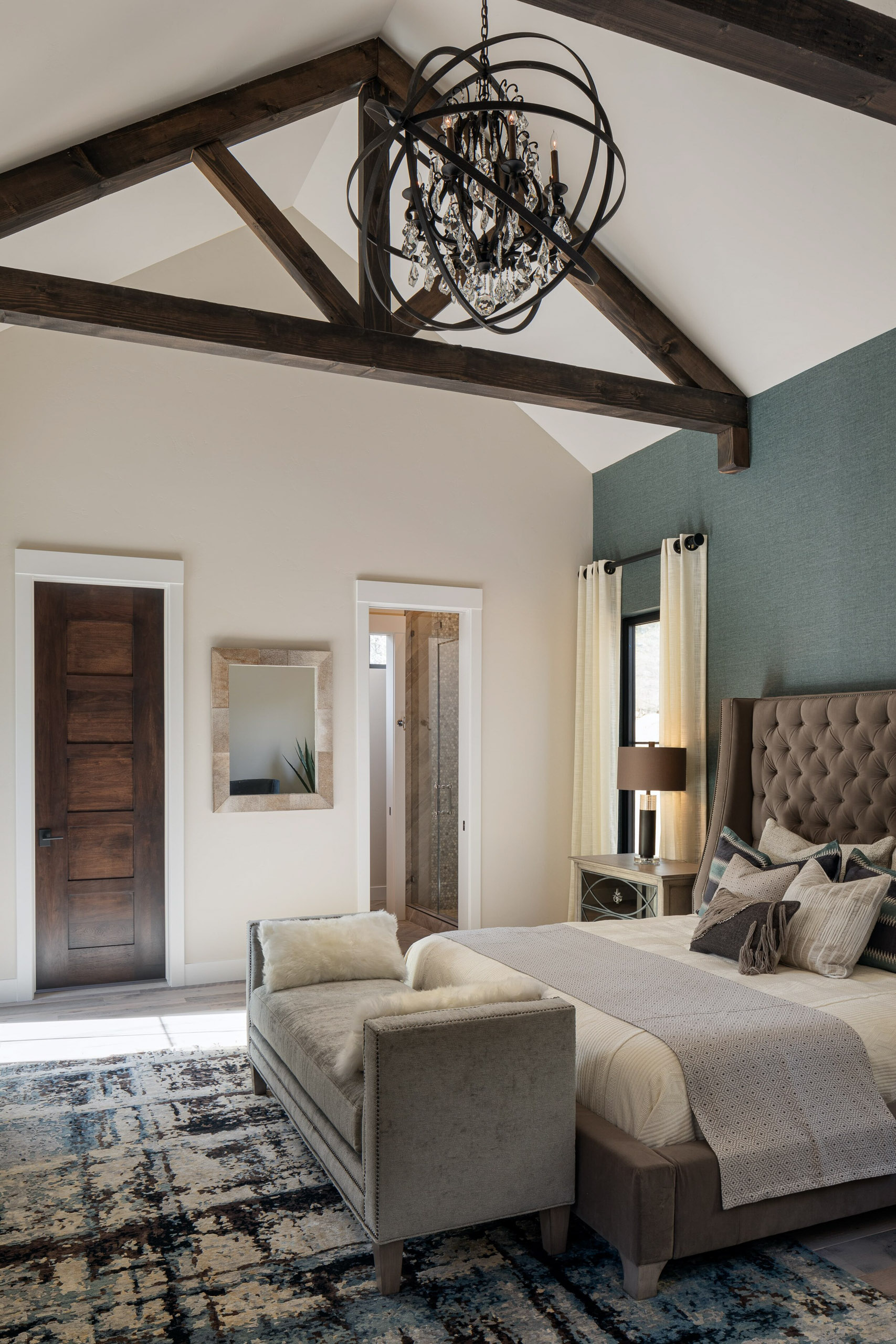 Bedroom with vaulted wood-beamed ceiling and chandelier.