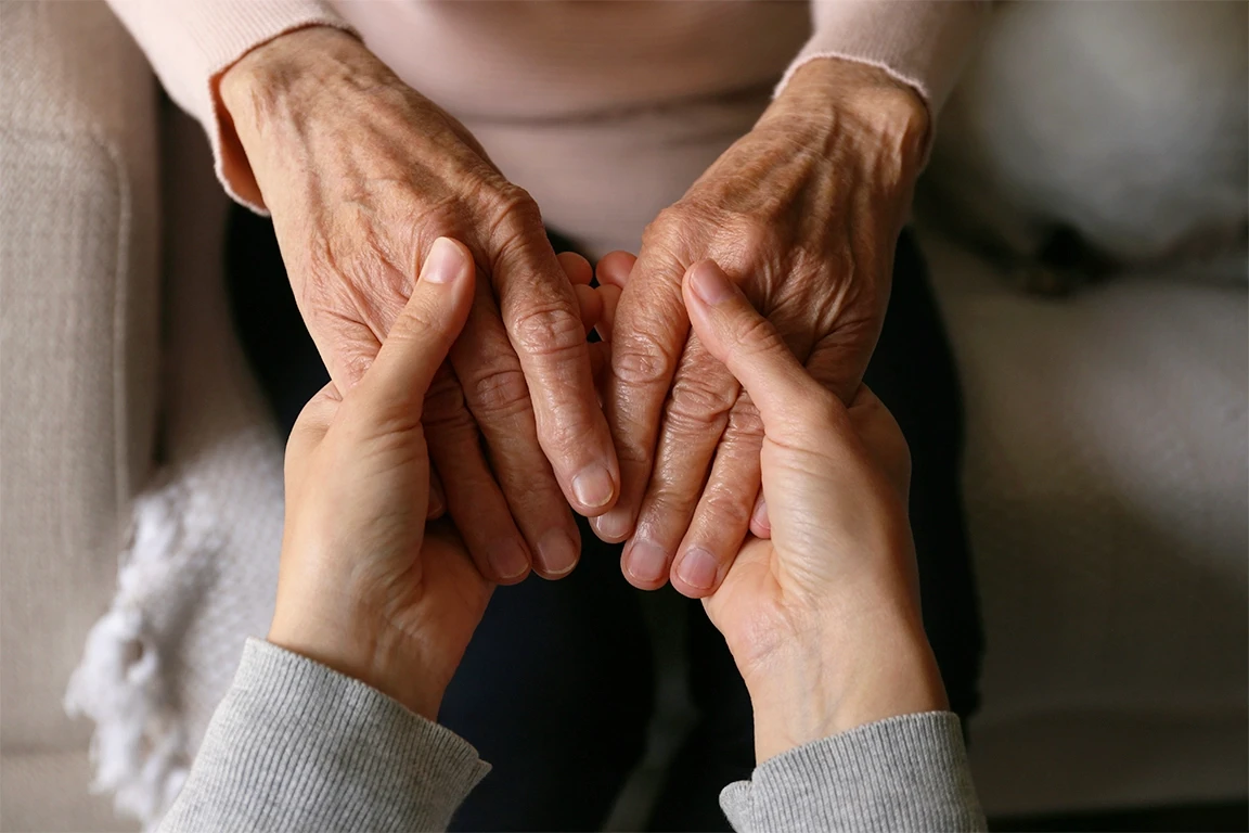 Hands of a caregiver and elderly resident held together, illustrating the emotional impact and vulnerability involved in nursing home abuse cases