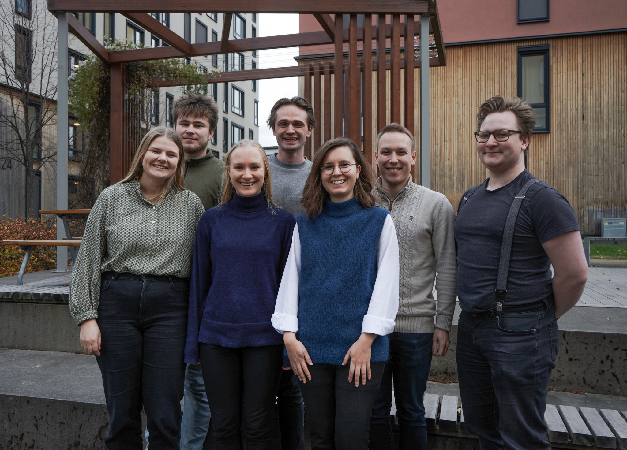7 smiling Aneo trainees in front of the Energy Building at Lerkendal