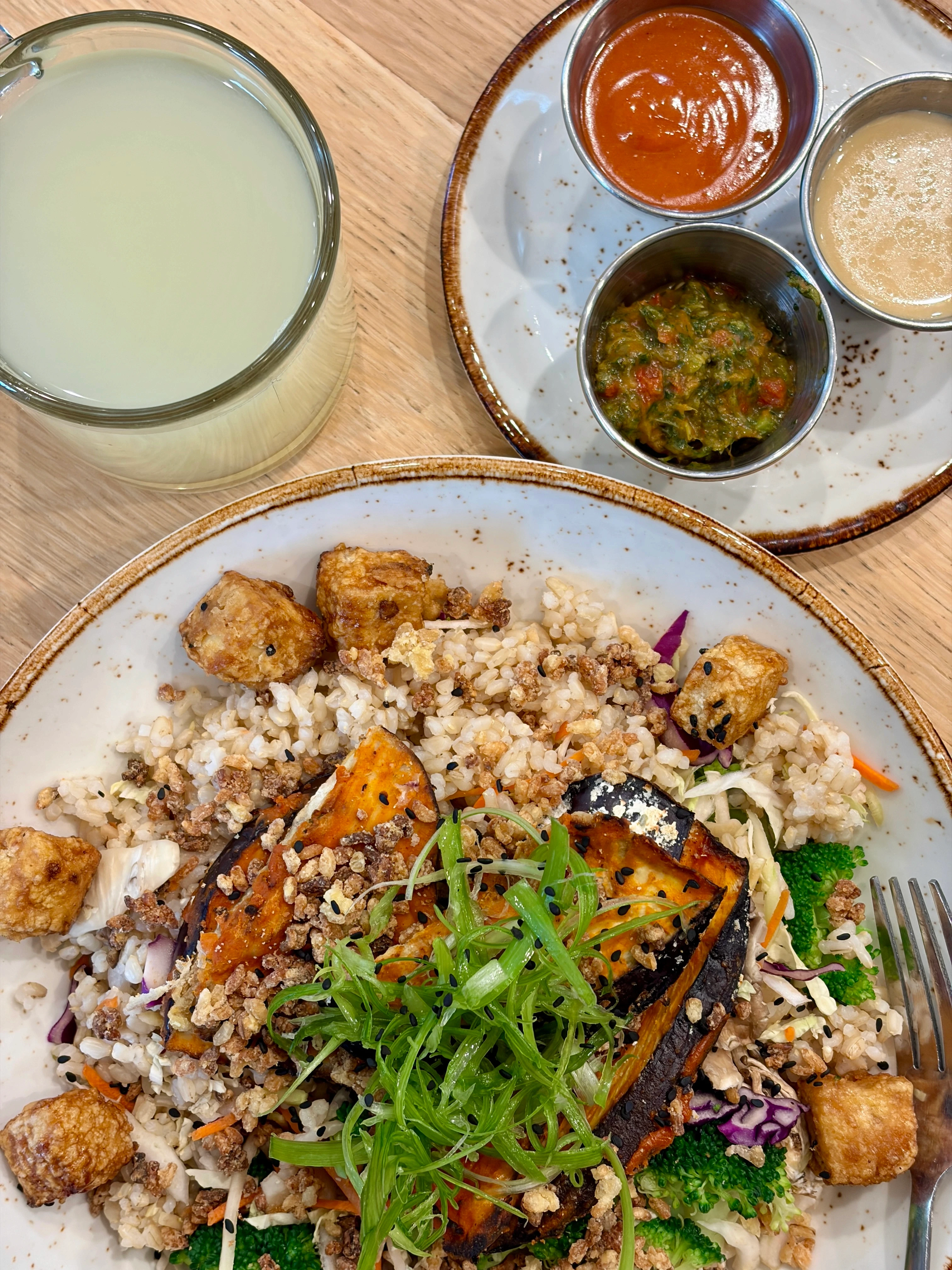 Life Alive Organic cafe meal with a side of tea and a crispy egg plant and tofu bowl on spotted plates with sauces on the side