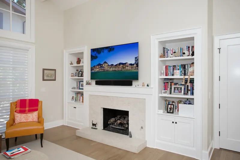 Den with hardwood flooring, stone clad fireplace and built-in cabinets with a wall mounted TV from the Big Canyon Remodel project. Photo by Chris Darnall.