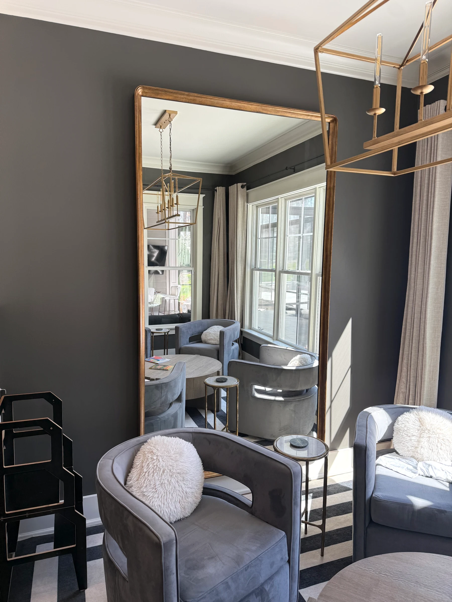 Tall gold mirror in a dining room beside patterned seating.