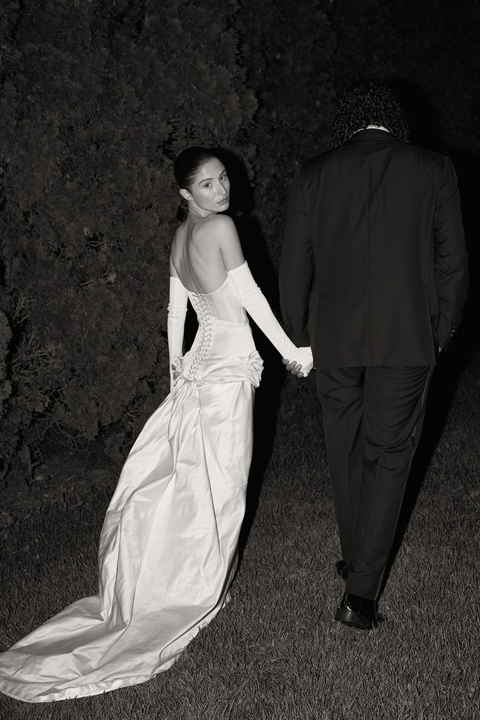 Black-and-white flash photograph of bride and groom walking hand in hand at night
