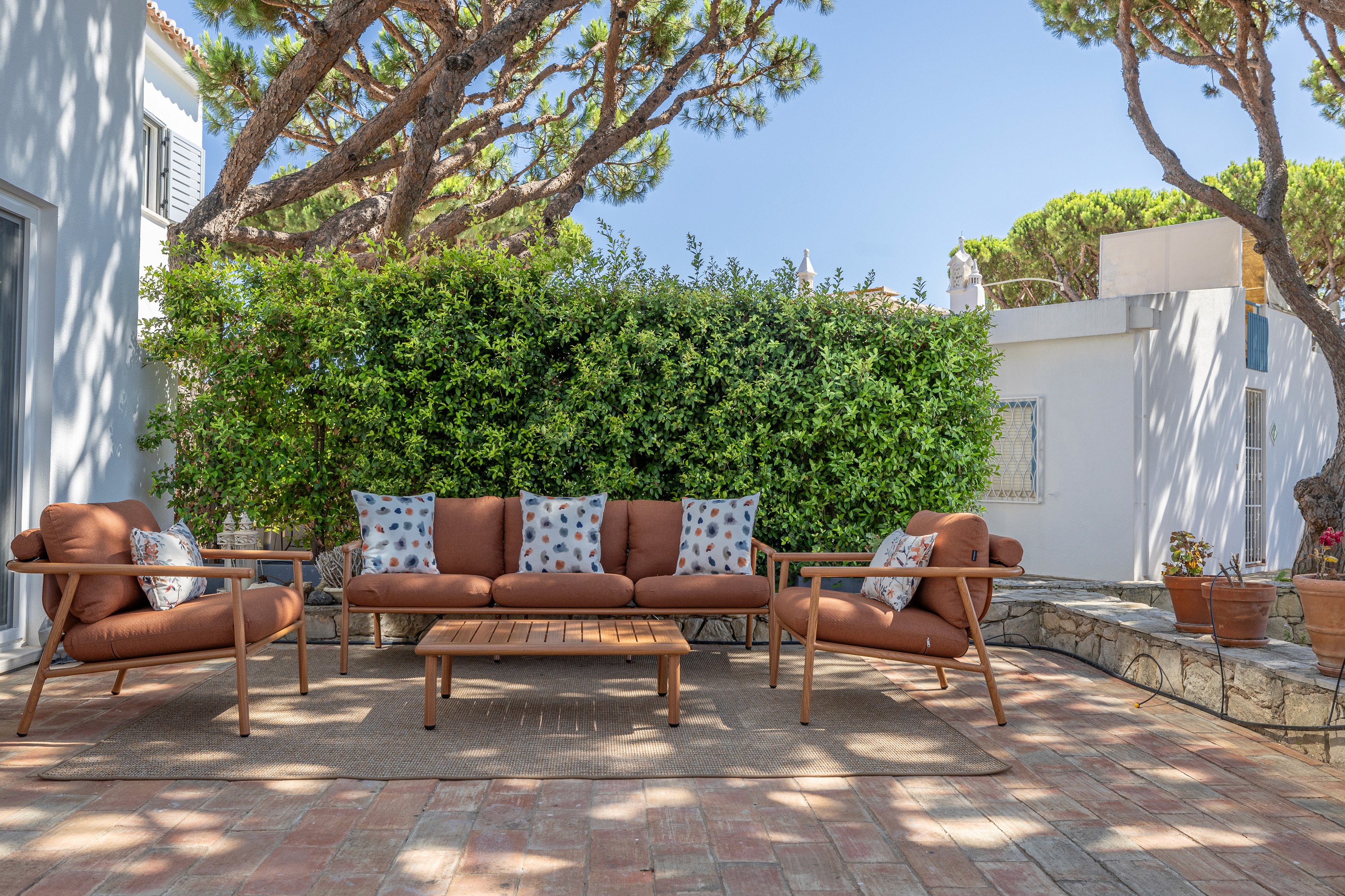 Terrace seating in rust-toned leather under umbrella pines