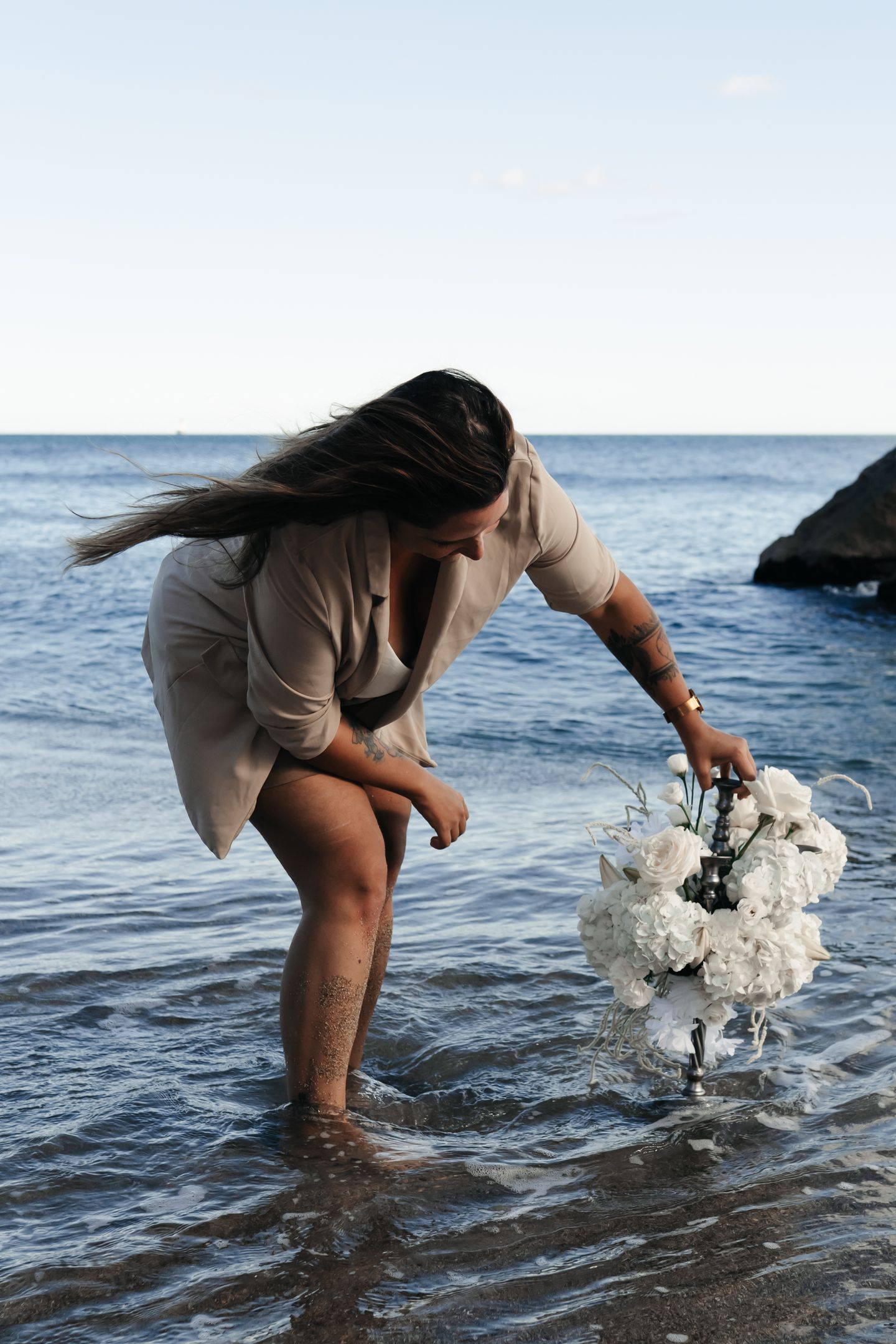 A person with shoulder-length blonde hair wearing a black newsboy cap and a black sweater.