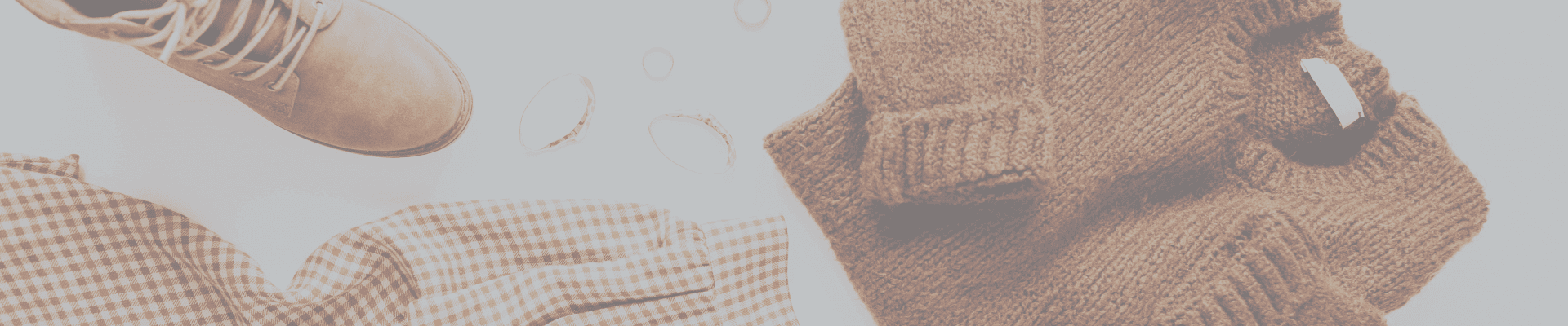 Cozy fall clothes, boots, and accessories laid out – wardrobe staples to include in a seasonal college packing list.