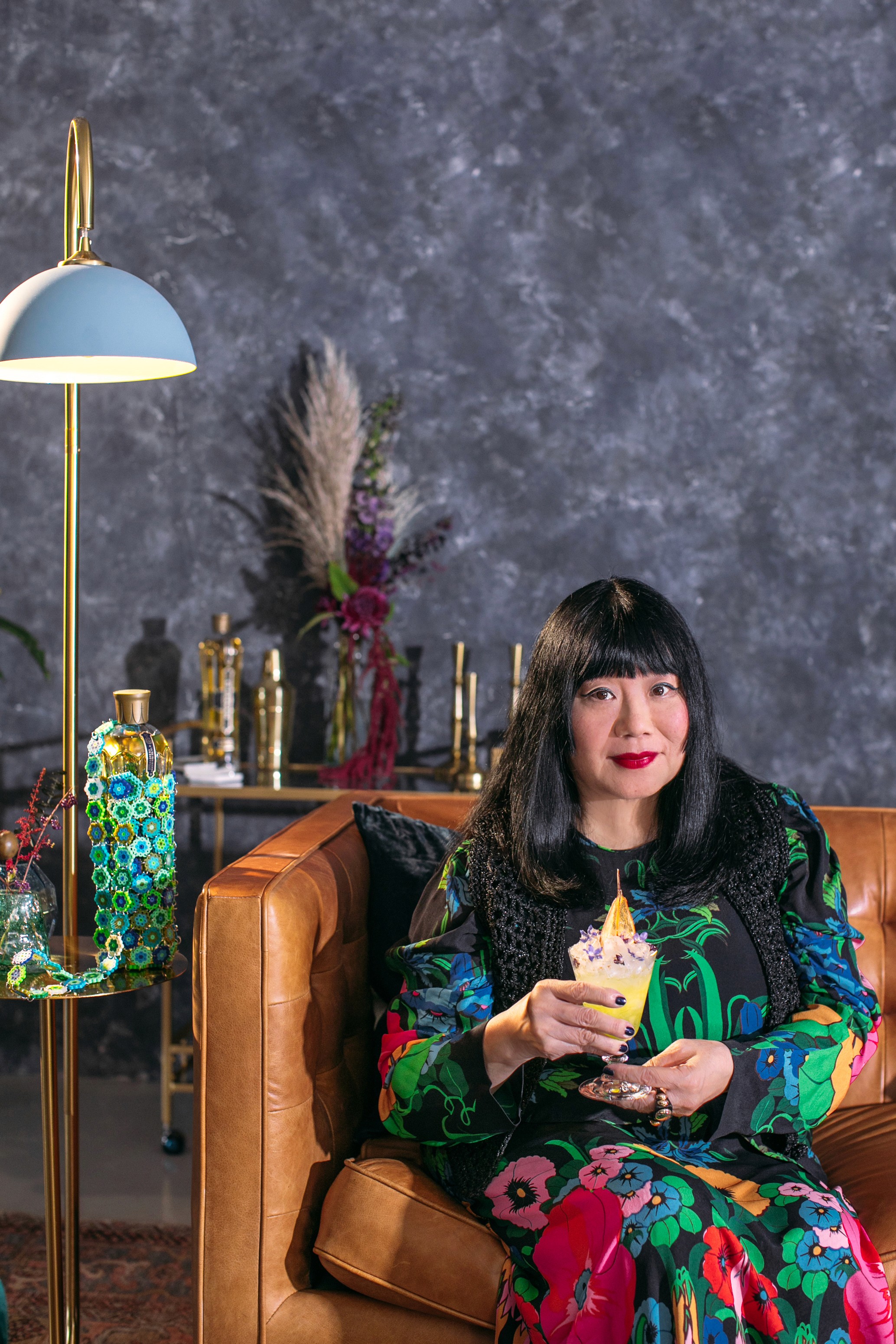 Anna Sui seated with a St-Germain cocktail in the holiday campaign lounge set